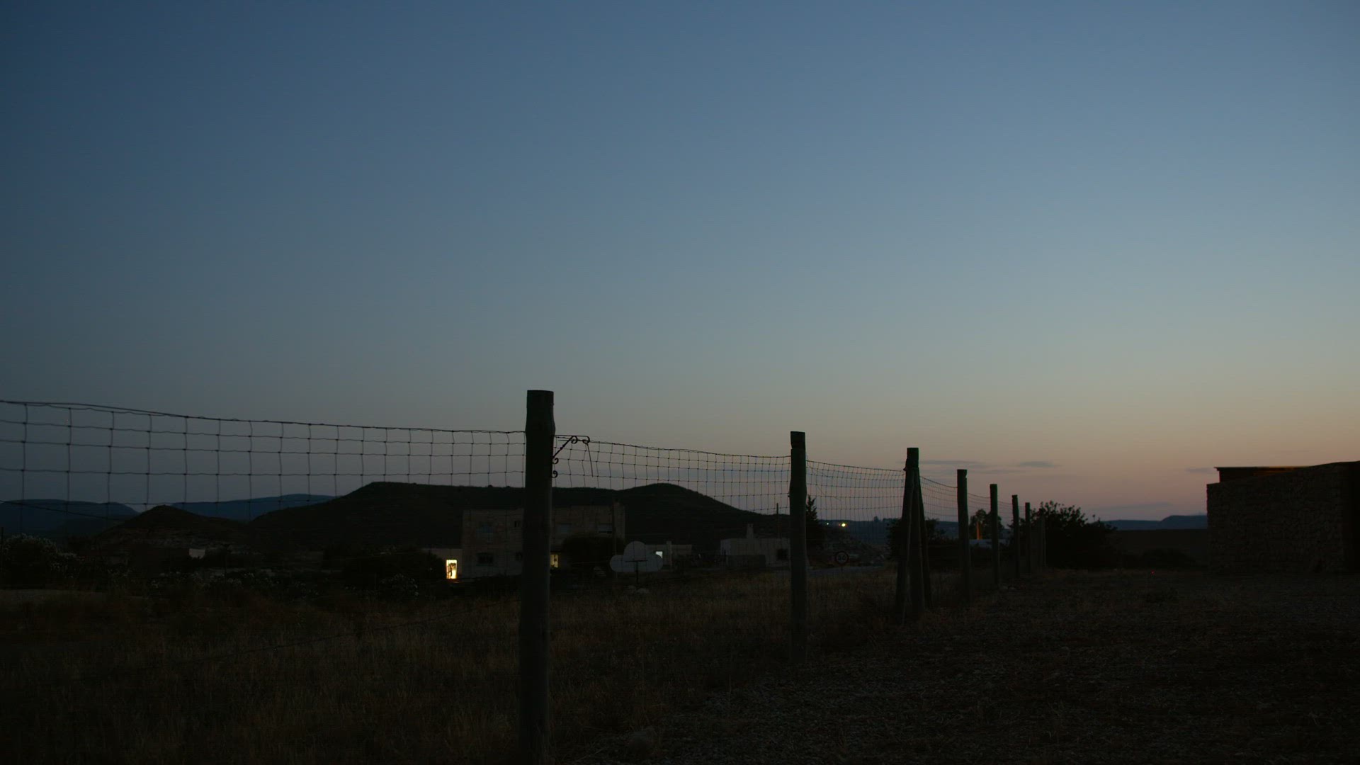 Car on the country road with wire metal fence alongside, dusk view