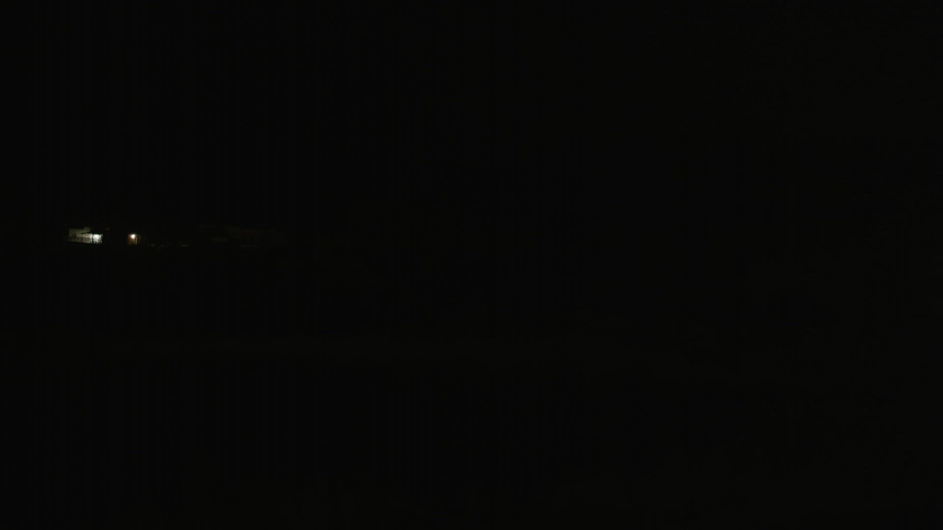 Pitch darkness and a car with lit headlamps passing by on country road