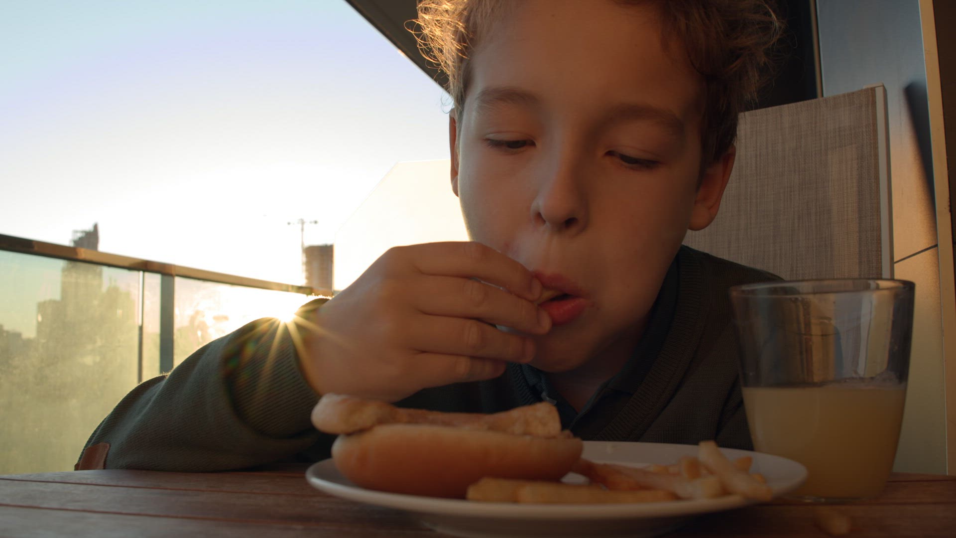 Boy eating French fries with orange juice for breakfast