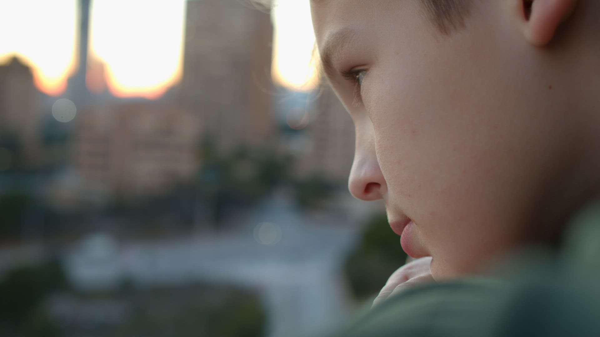 Boy with sad look staring at the city from the balcony
