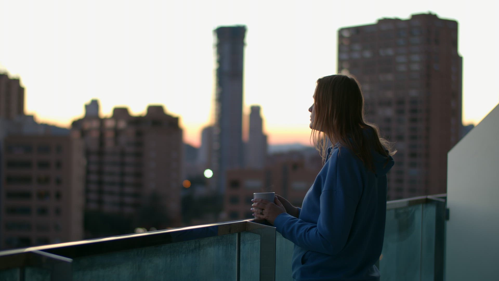 Urban woman drinking tea on the balcony in early morning