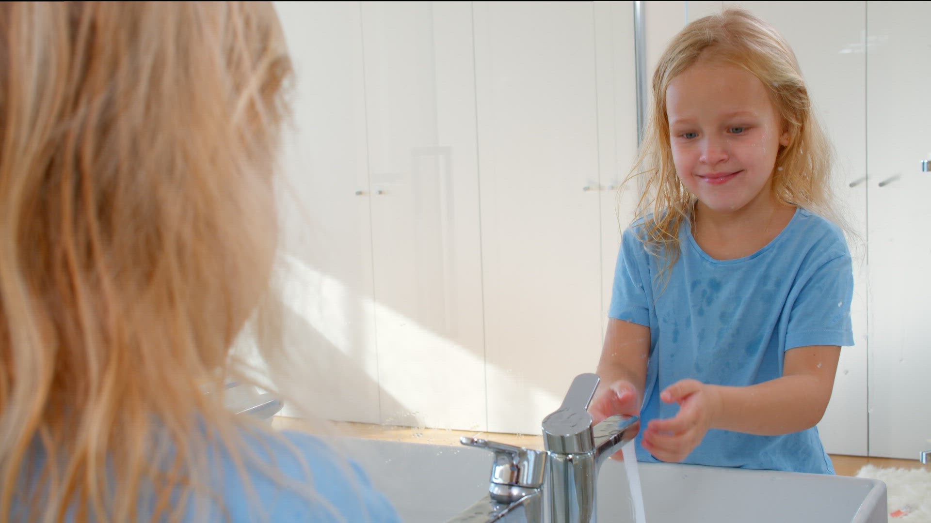 Girl washing face and smiling at reflection