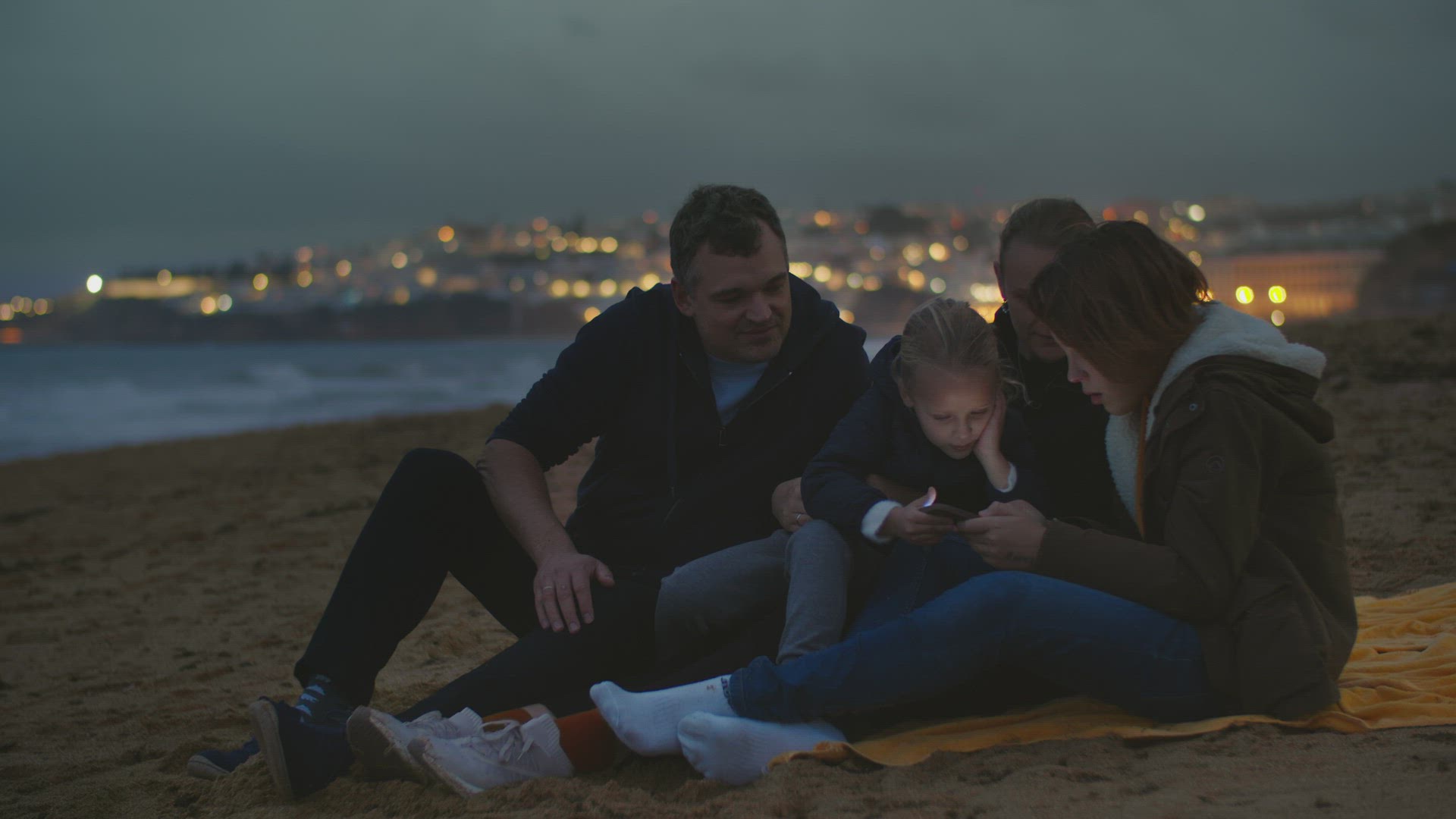 Family watching phone on ocean shore