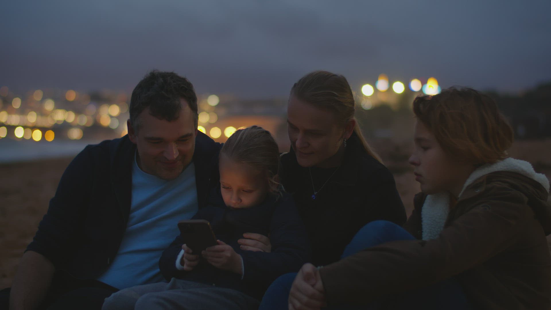 Family Watching Screen on Ocean Beach
