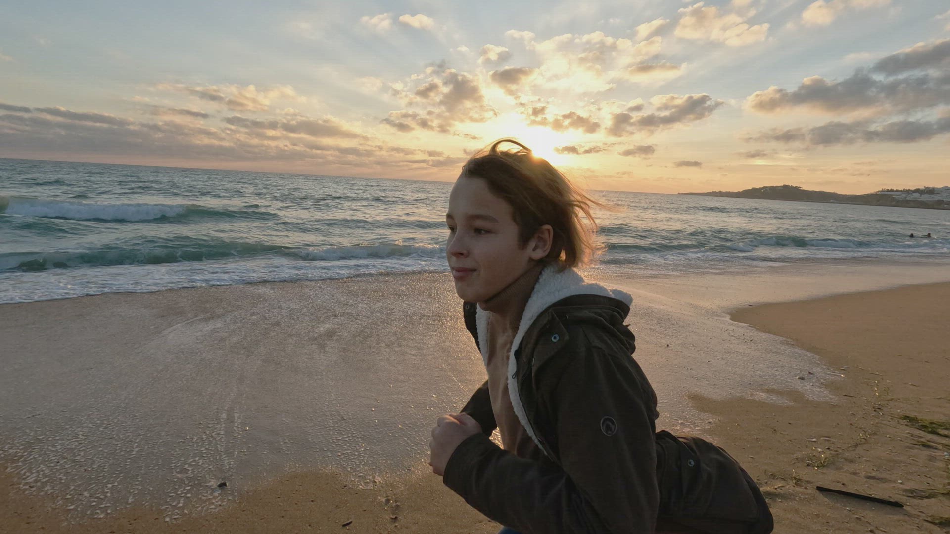 Teen running on sandy beach at sunset