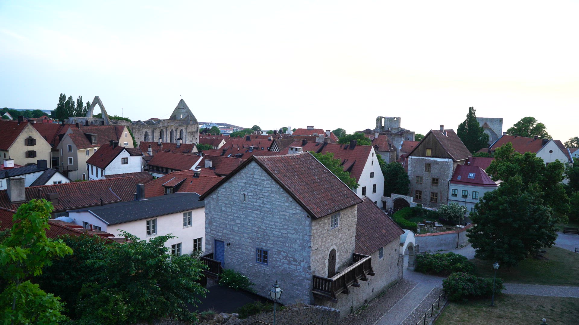 view over central Visby at dusk - evening shot - people walking in street - gotland