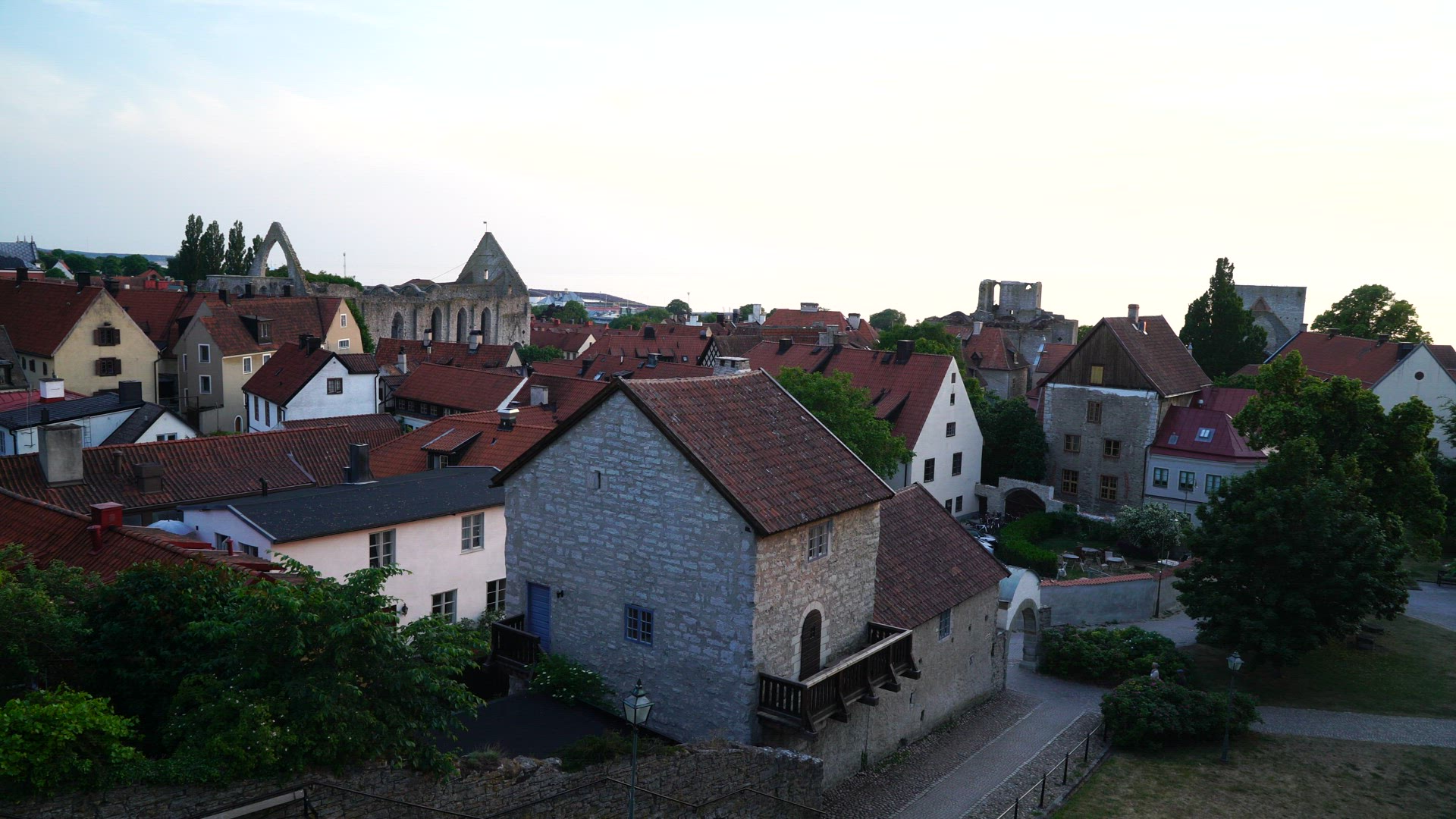 view over central Visby at dusk - evening shot - people walking in street - gotland