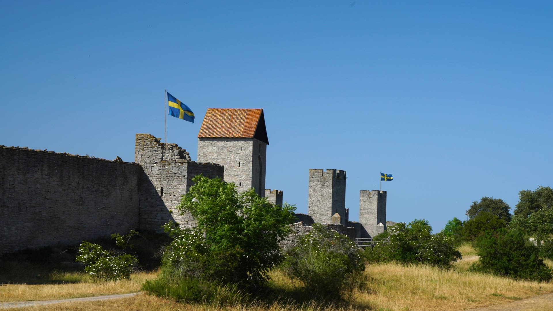 Visby City Wall - people on bicycles - walking - swedish flags in strong wind