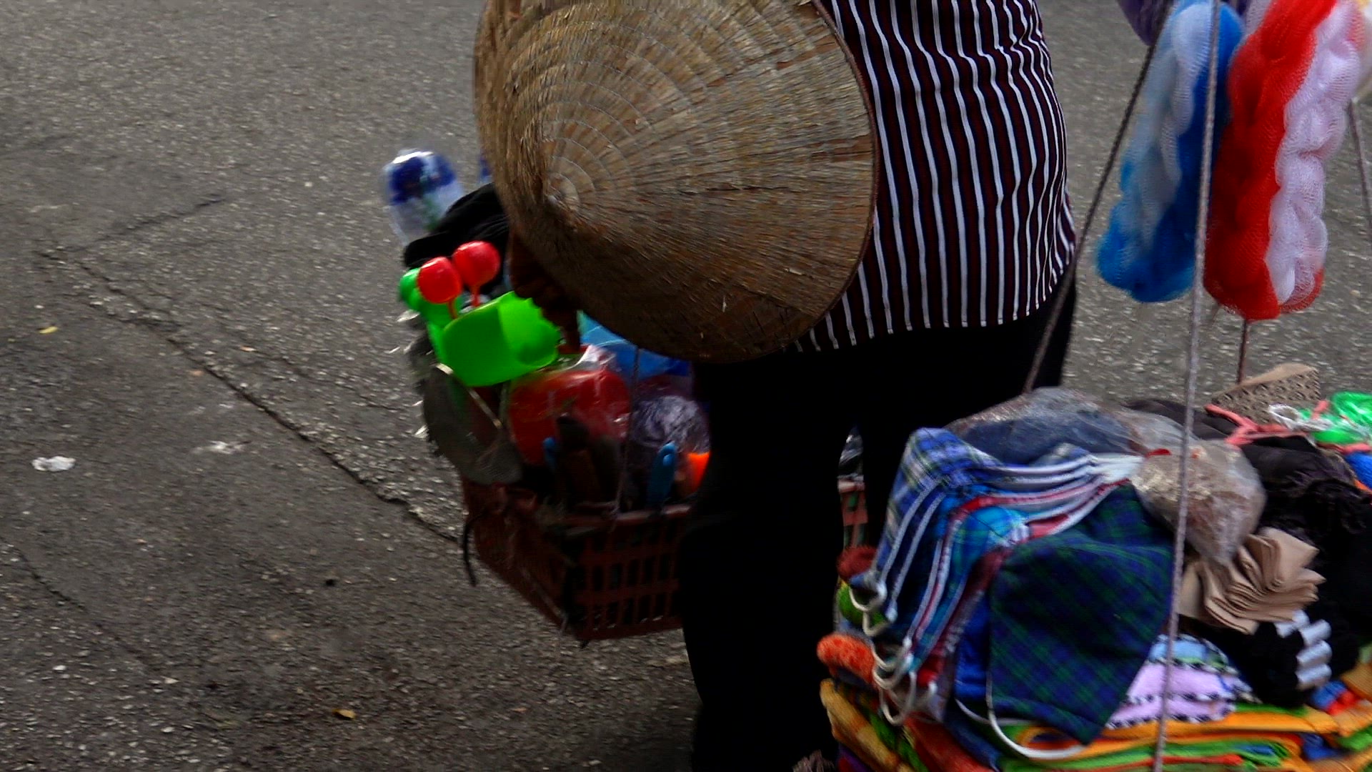 Vendor carrying loads of clothing in a market in Vietnam