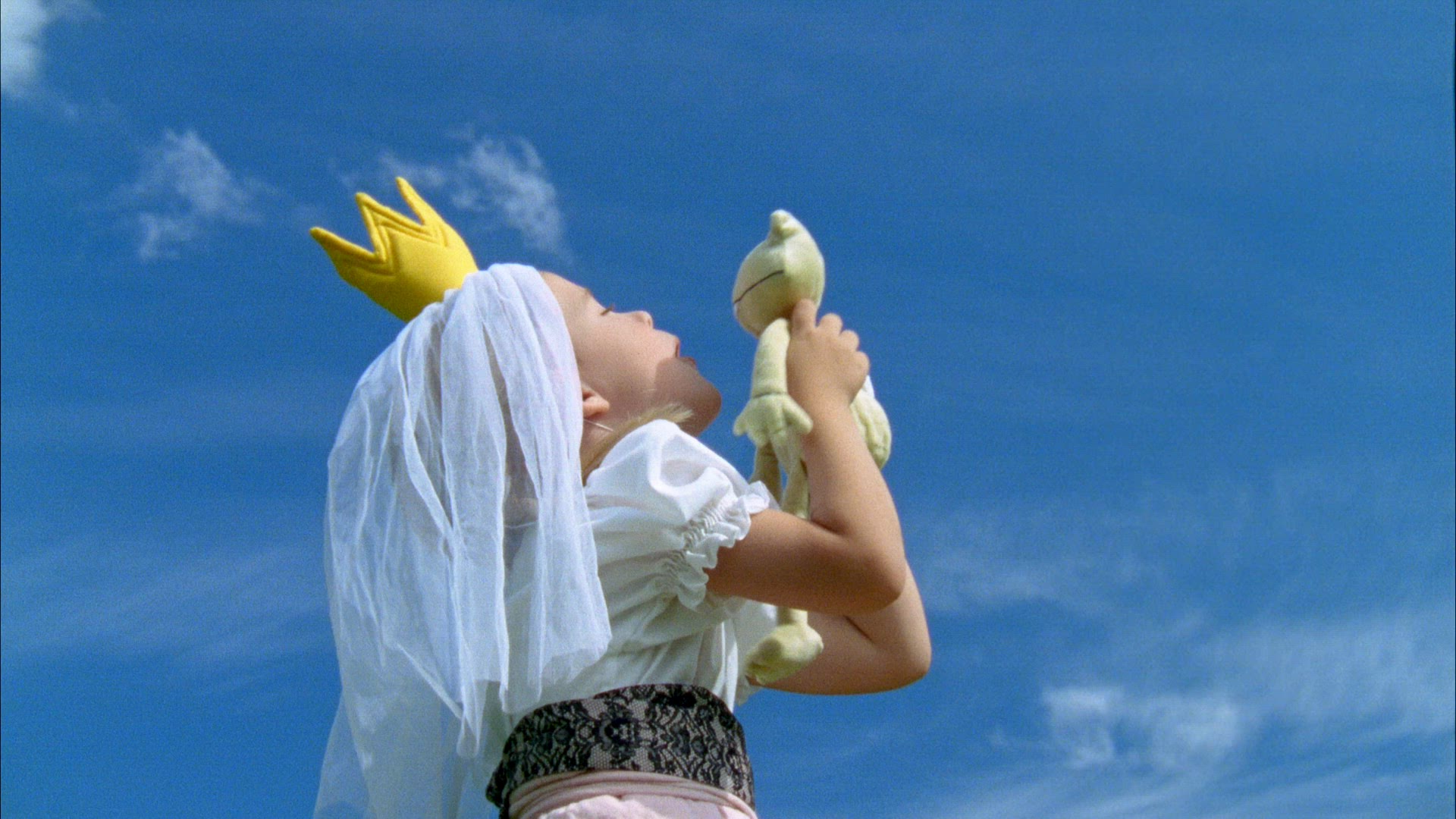 young girl kisses a toy frog - girl dressed as princess