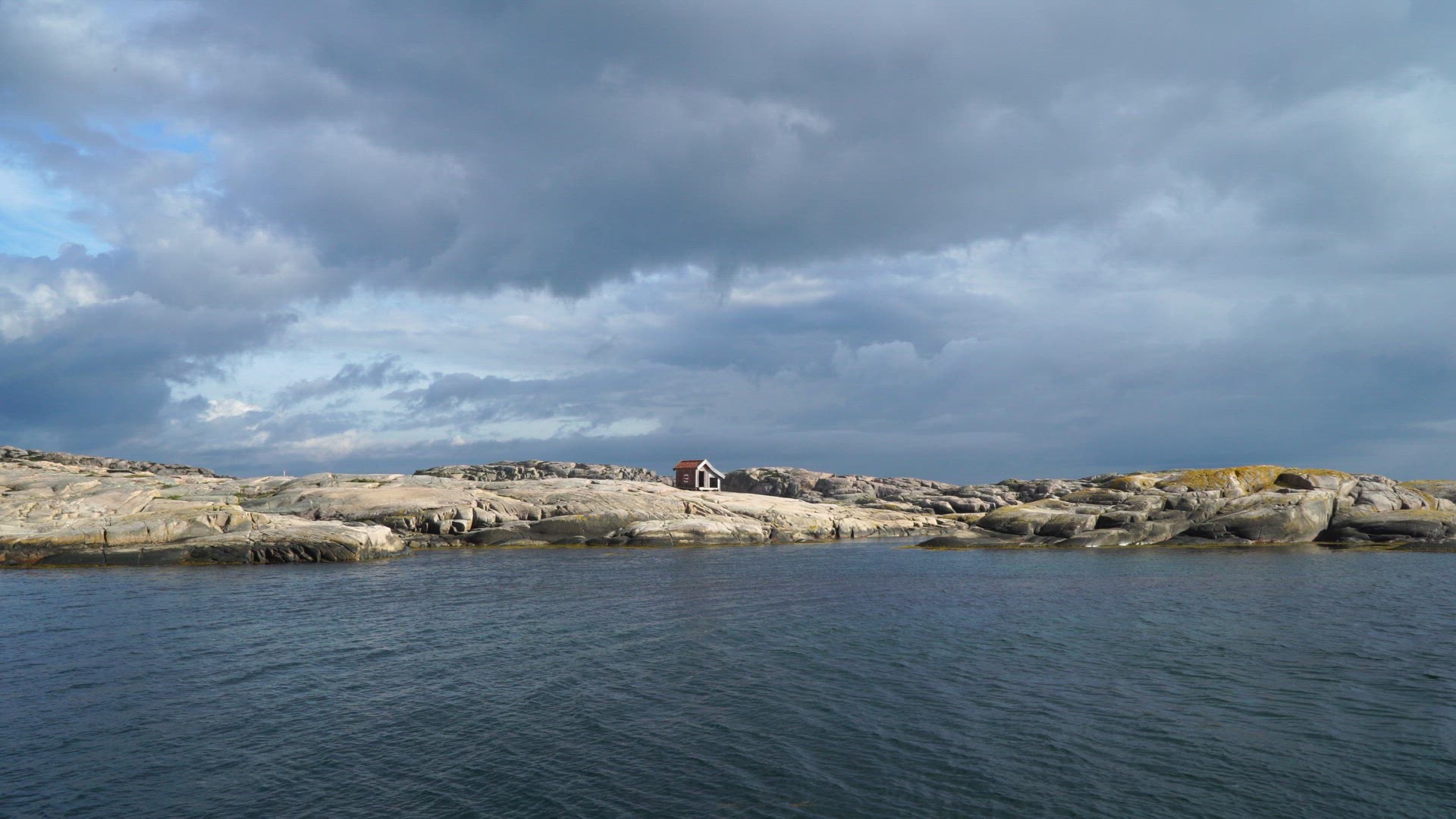 view over sea and cliffs with small red house in Bohuslän Sweden - fishing shed