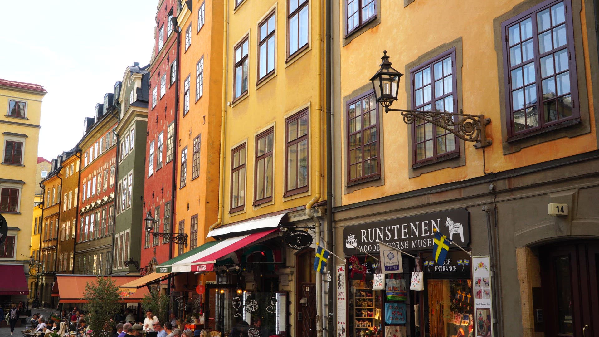 facades of buildings in old town in stockholm - restaurants with people 