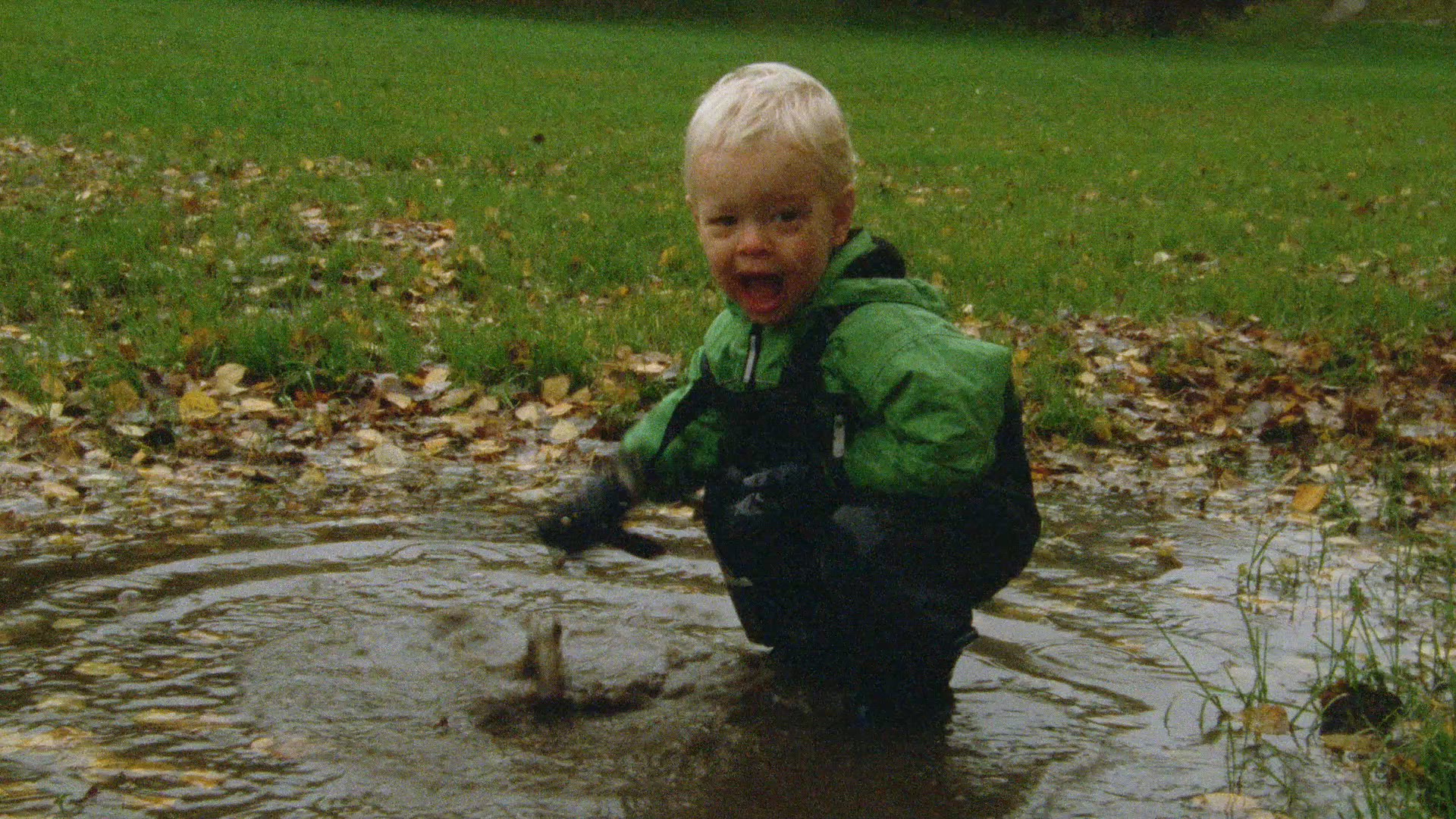boy playing in muddy dirty water - autumn leaves
