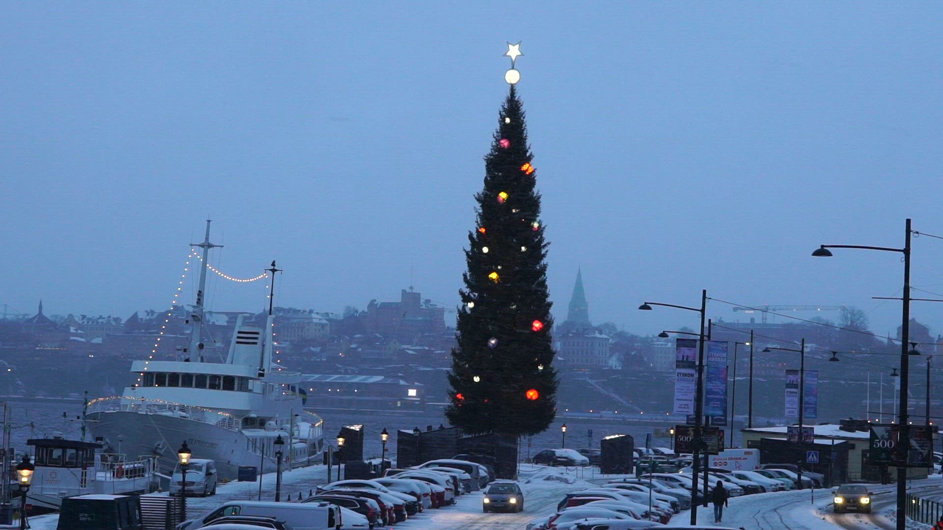 skeppsbron in stockholm - boats at quay - decorated christmas tree - snowfall and strong wind