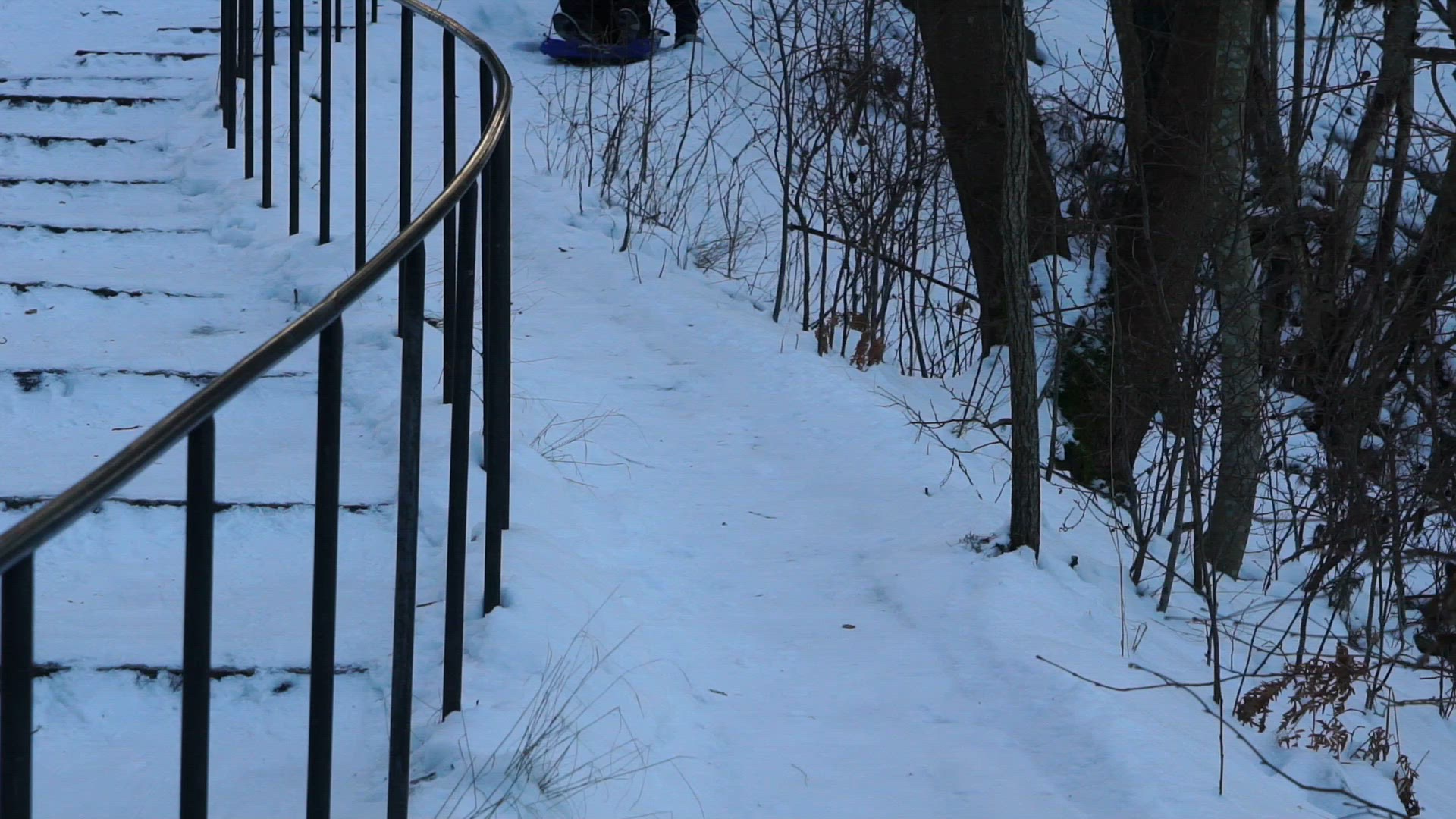 boy riding in snow on plastic mattress