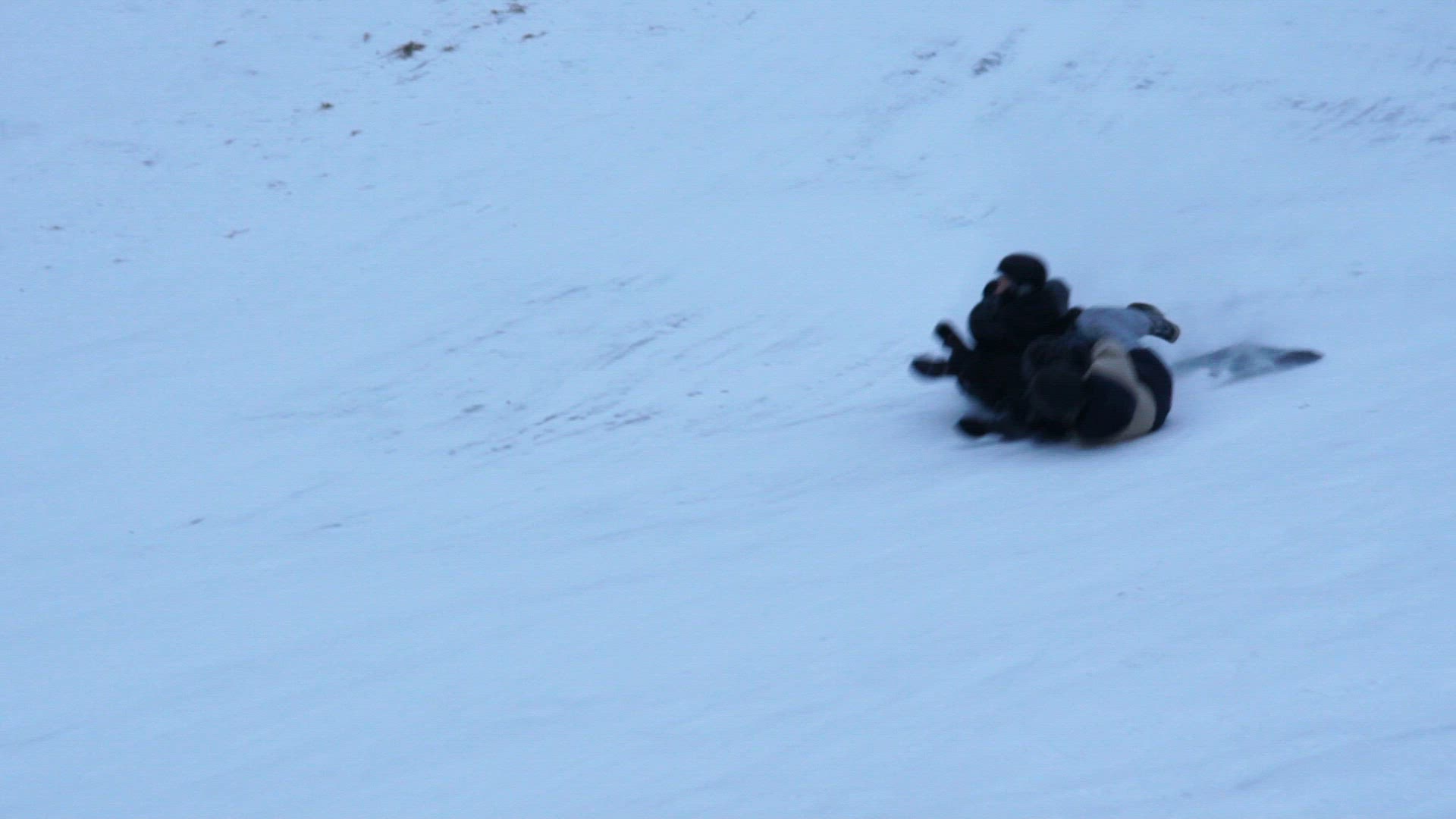three boys going downhill in skislope on plastic mattress - snow spraying - 