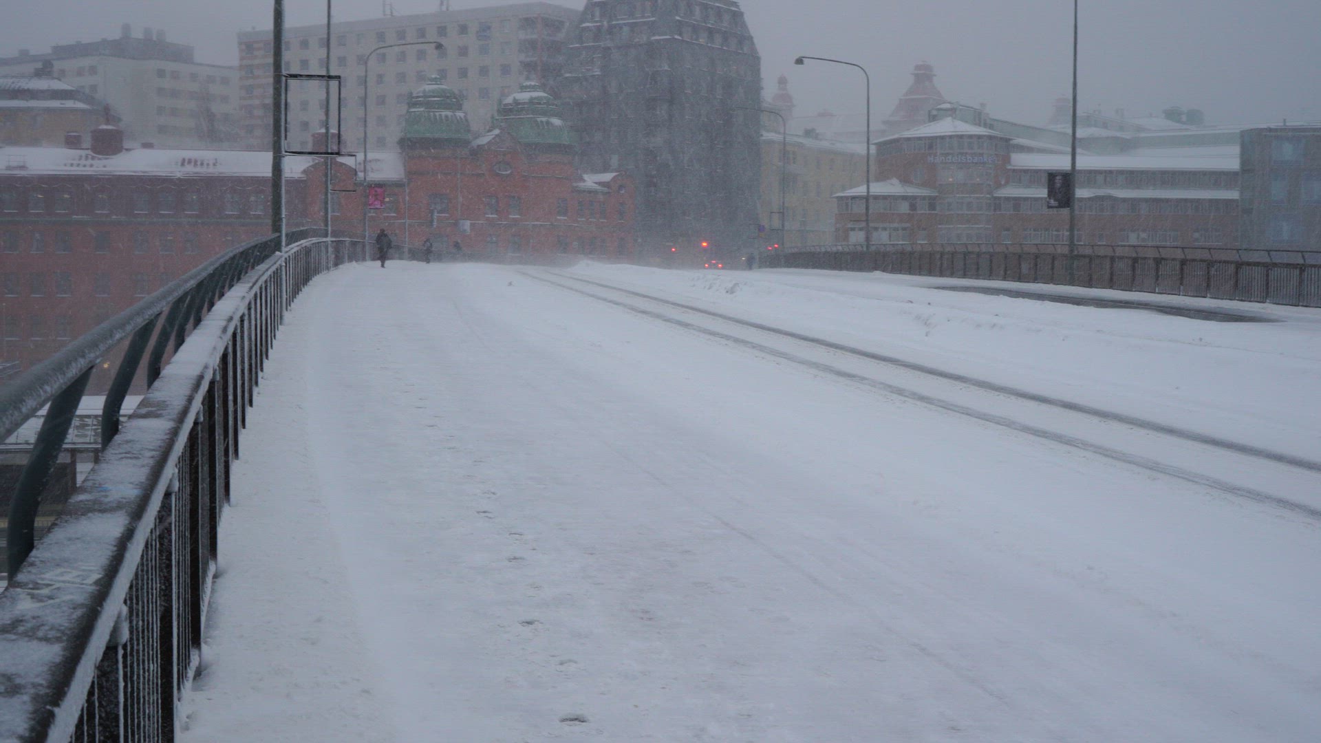 people walking on bridge in stockholm in heavy snowfall and strong wind - umbrella
