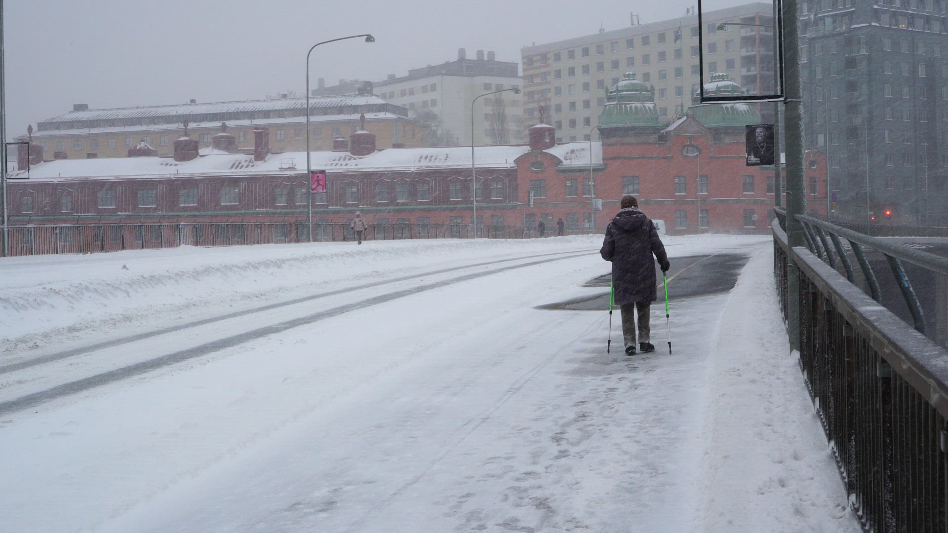 senior person walking with sticks on snowcovered sidewalk in central stockholm
