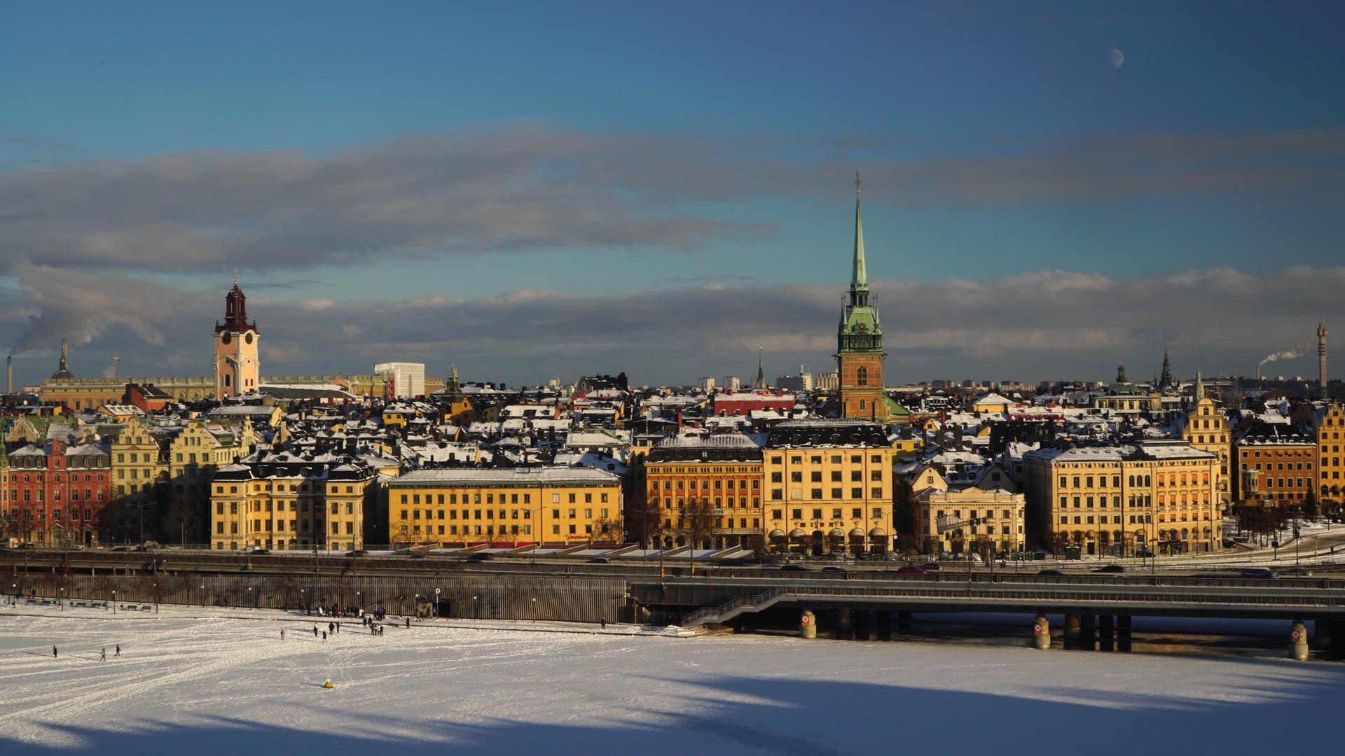 view over wintry stockholm - old town - people walking on ice in central stockholm - train passing -