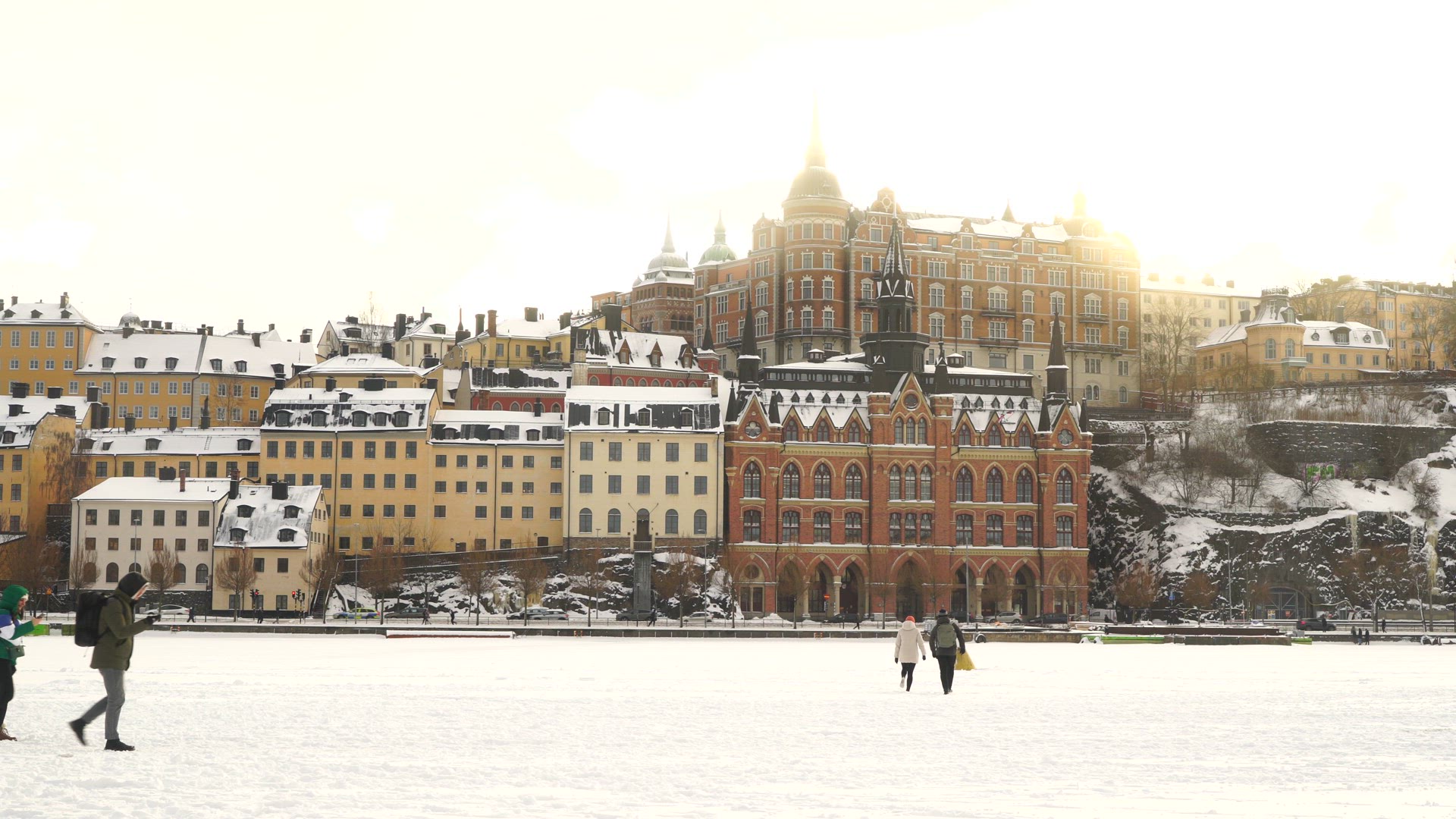 people walking on ice in central stockholm - mariaberget in background - wintertime
