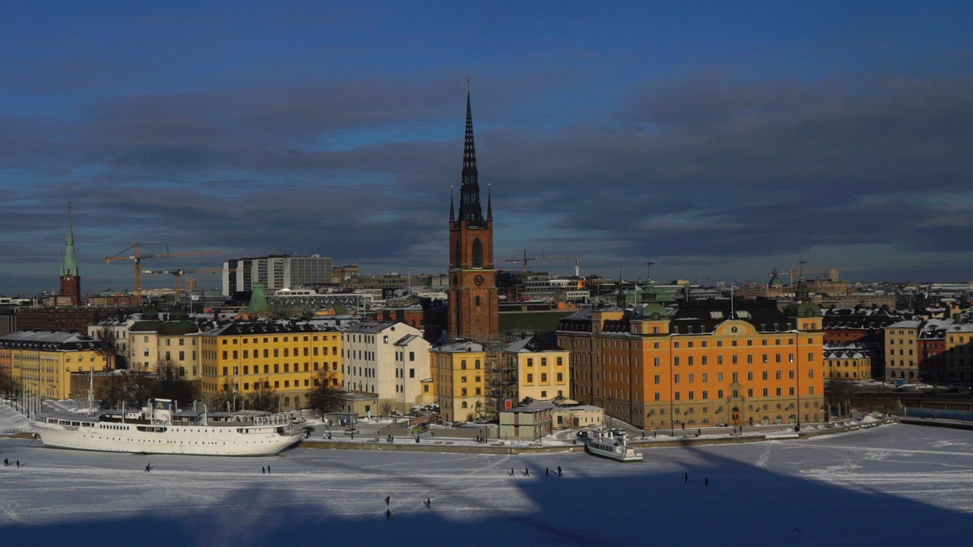 view over wintry stockholm - riddarholmen - people walking on ice - riddarfjärden - 