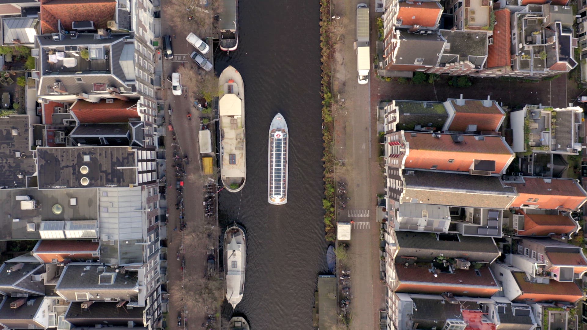 Canal Boat Tour in Amsterdam Amongst Riverside Houses Bird's Eye View