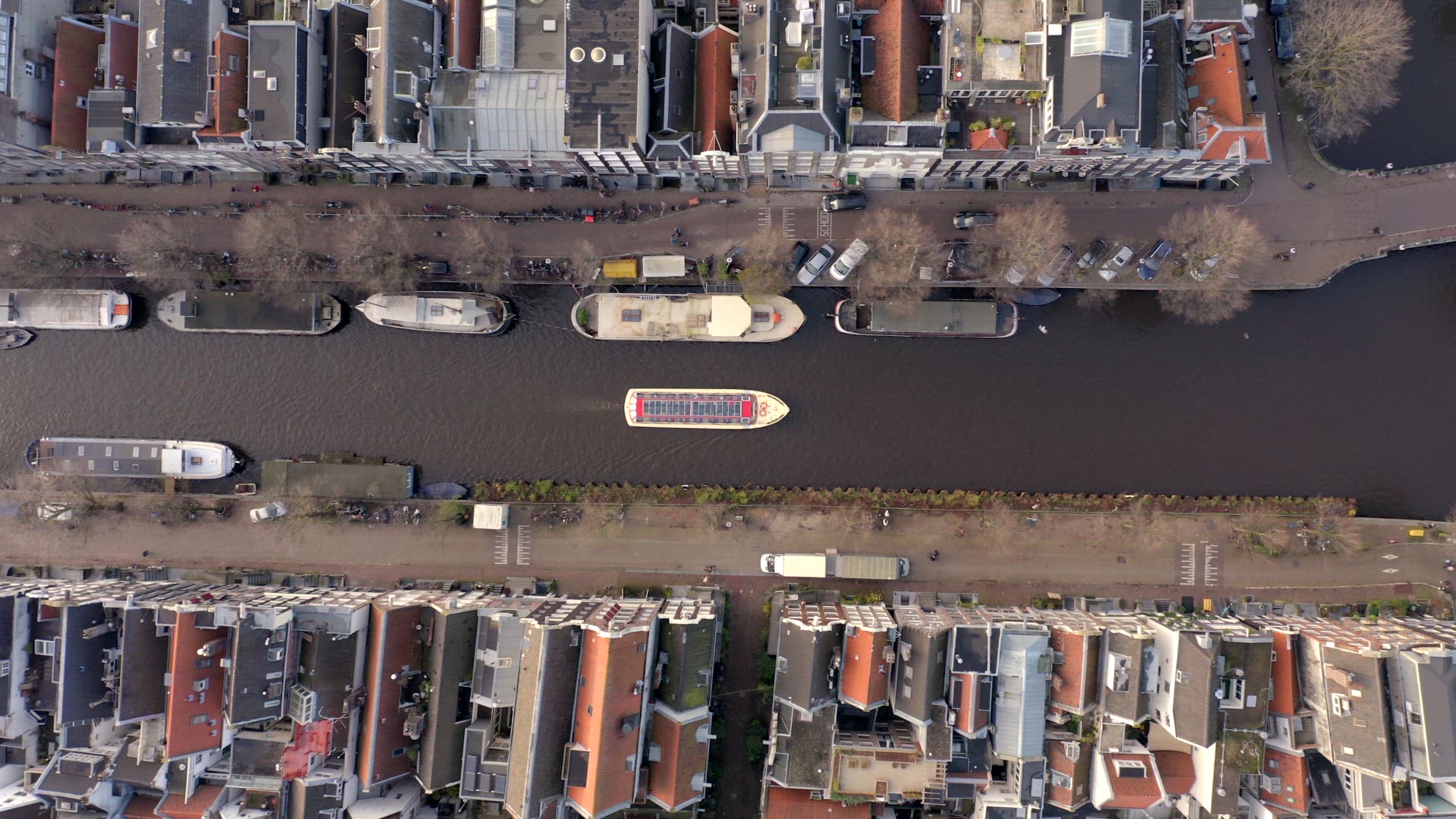 Canal Boat Tour in Amsterdam Amongst Riverside Houses Bird's Eye View