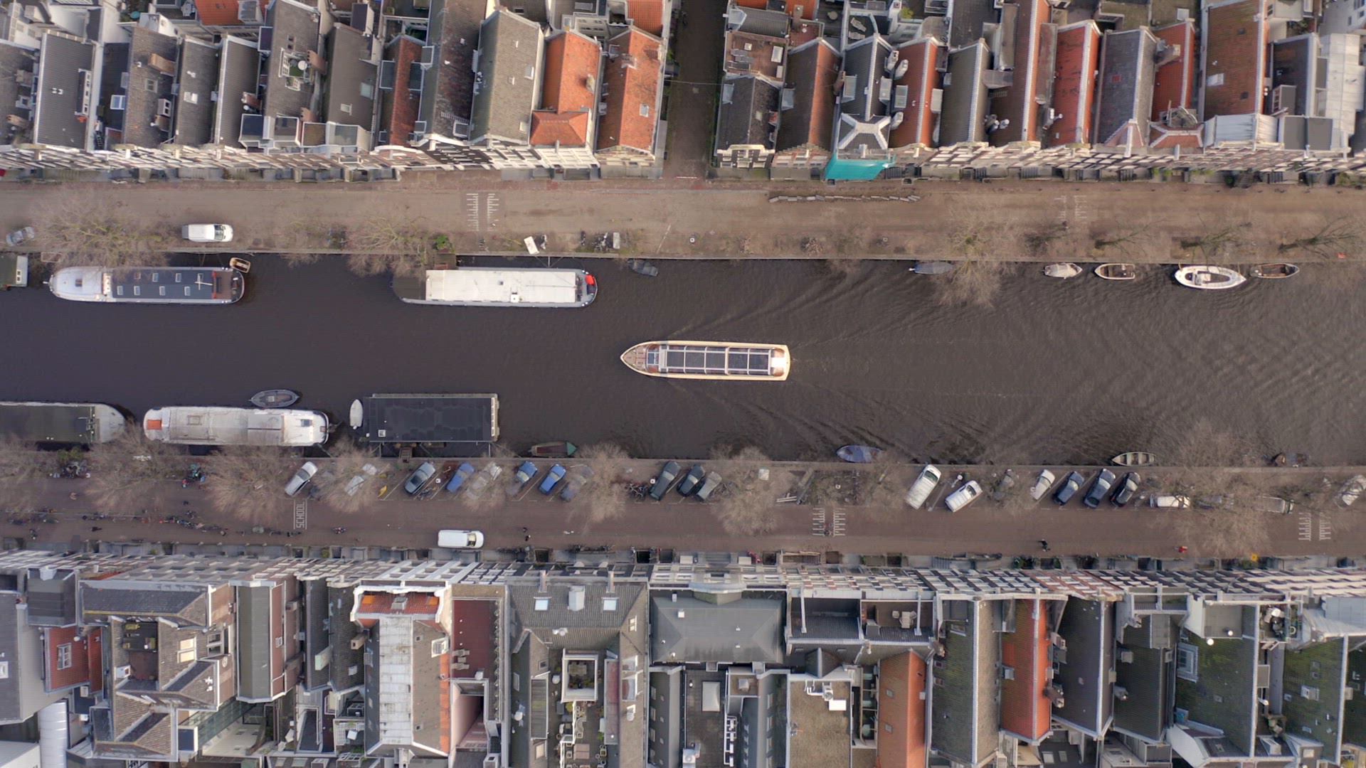 Canal Boat Tour in Amsterdam Amongst Riverside Houses Bird's Eye View