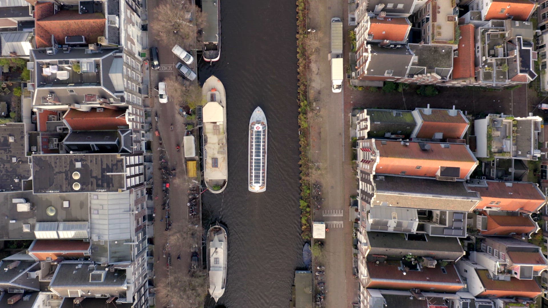 Canal Boat Tour in Amsterdam Amongst Riverside Houses Bird's Eye View