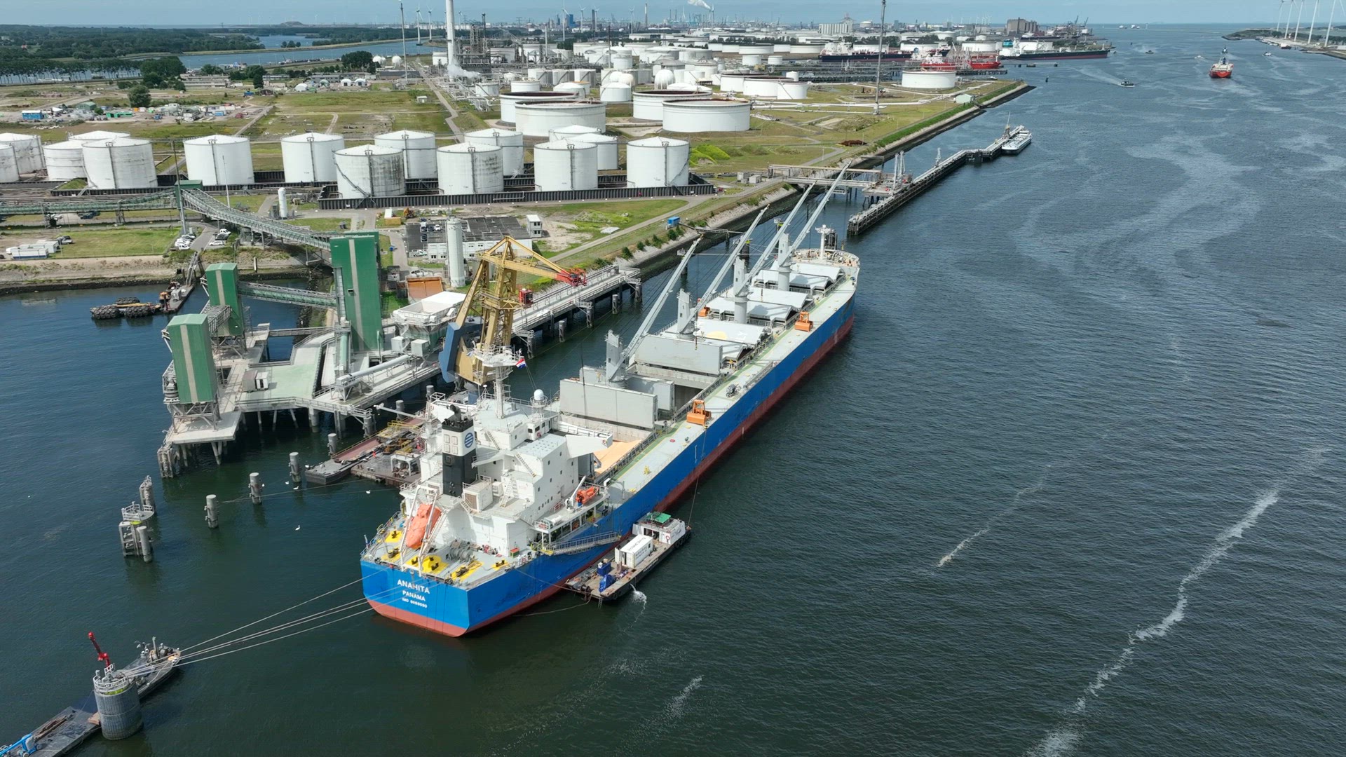 Bulk Carrier Ship at Port Offloading Cargo and Commodities by Shore Crane