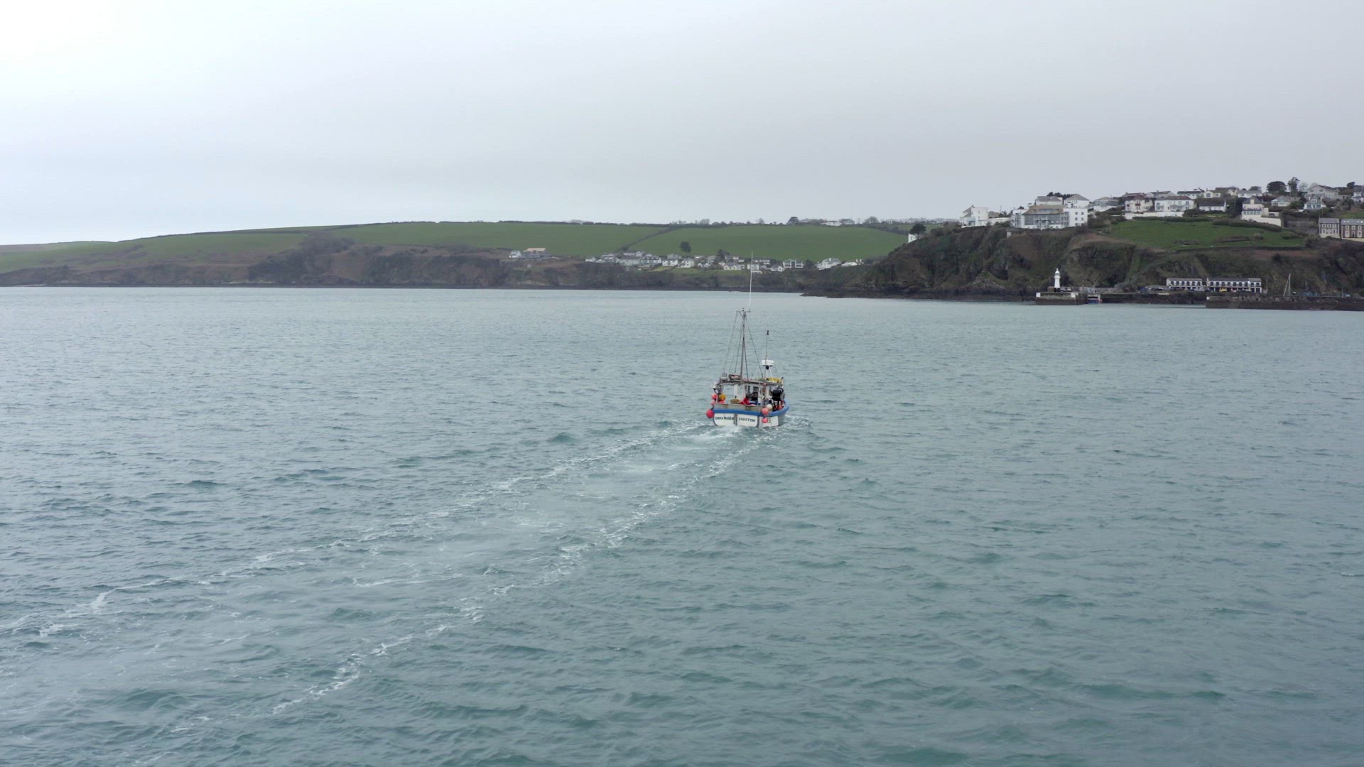 Fishing Boat Motoring at Sea With Tall Cliffs on a Grey Day