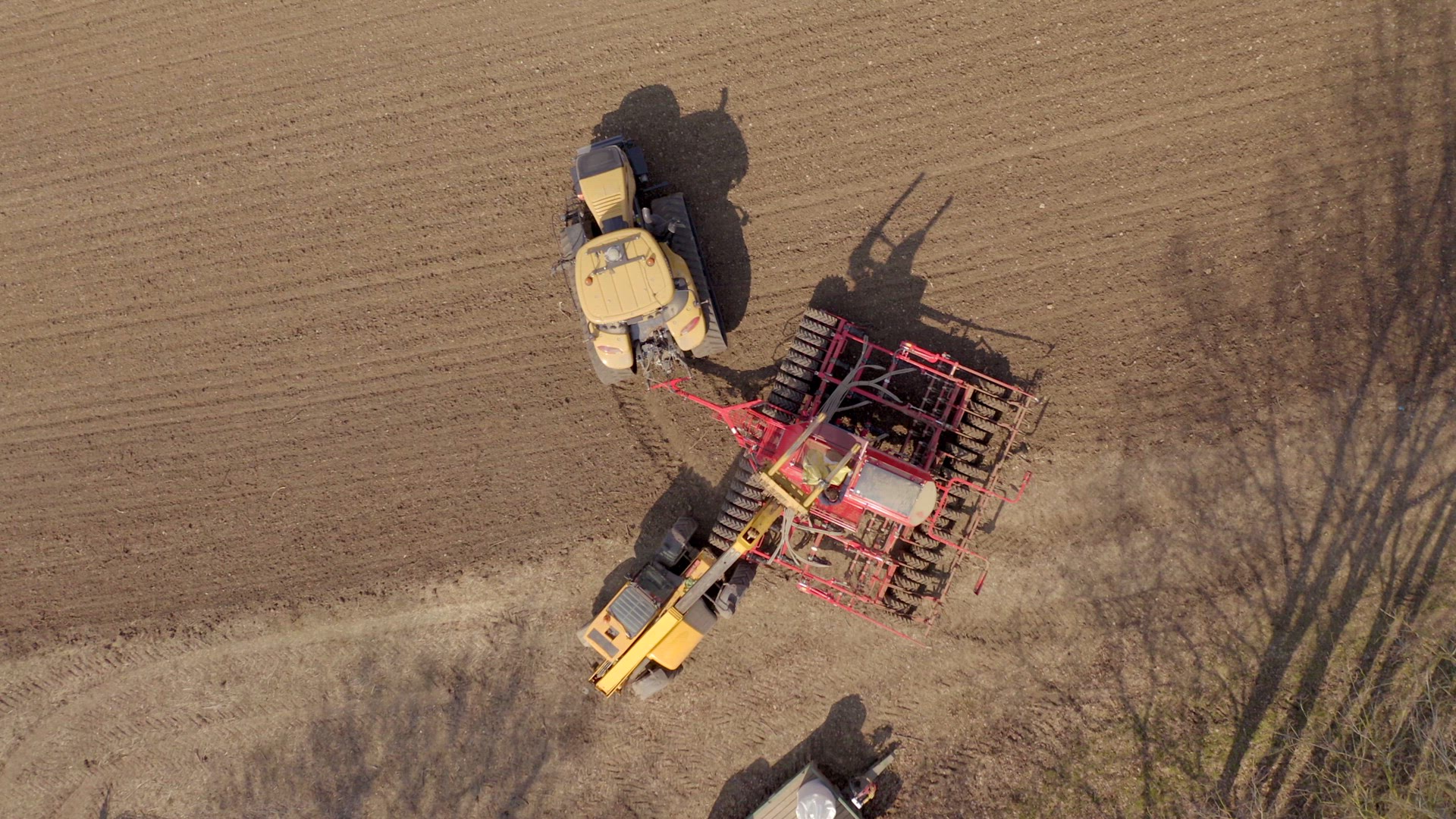 A Farmer Refilling a Seed Drill from a Bird's Eye View