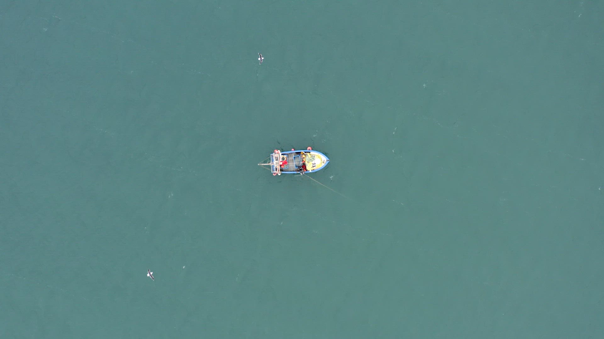 Fishing Crew Pulling Nets on a Small Boat at Sea