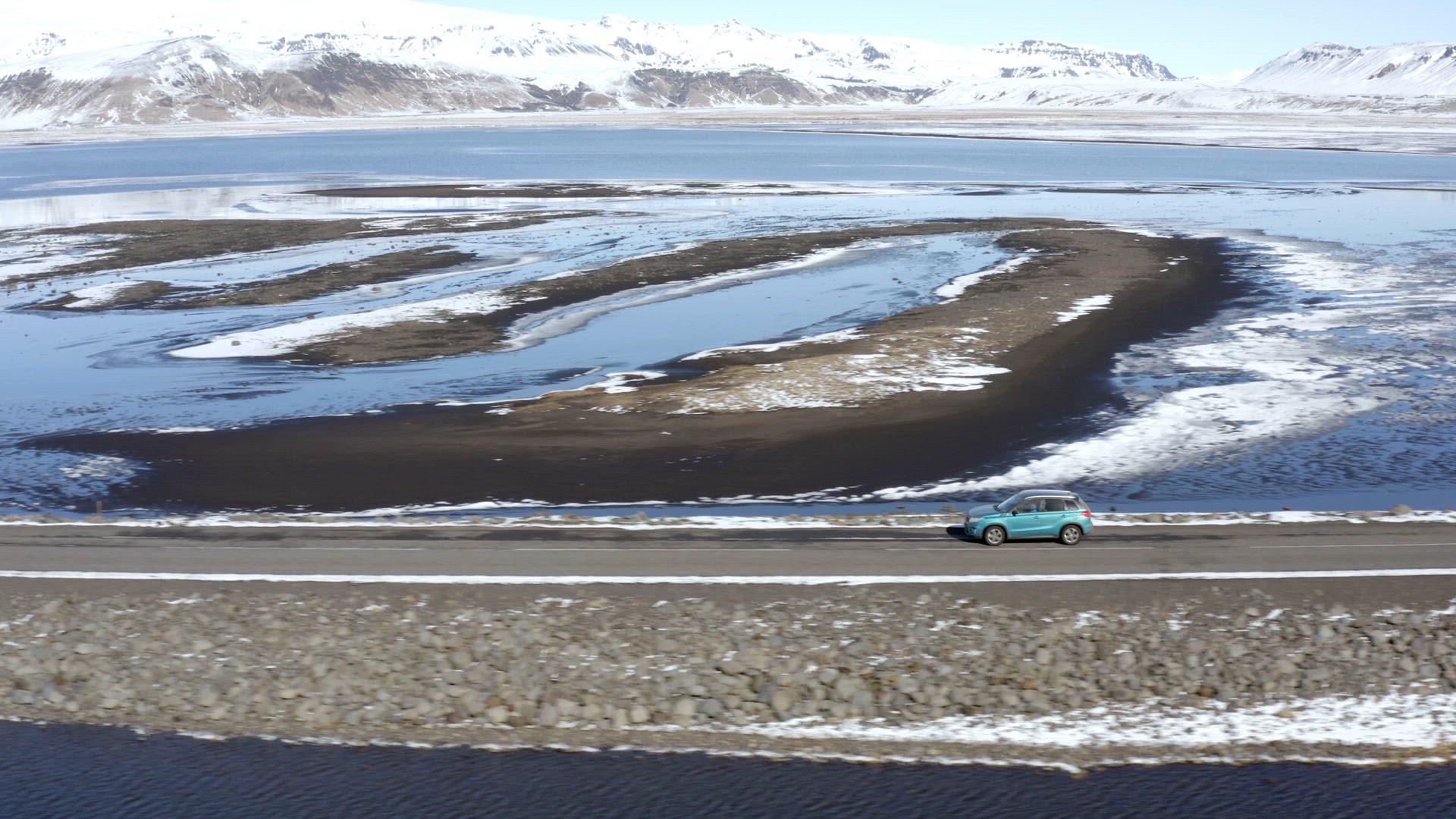 Car Driving Along a Narrow Road Over a Lake in Winter Conditions