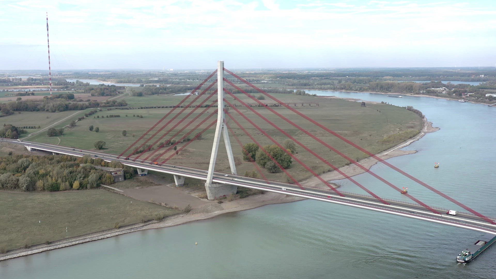 Barges Passing Under a Cable Stayed Suspension Bridge With Vehicles Crossing
