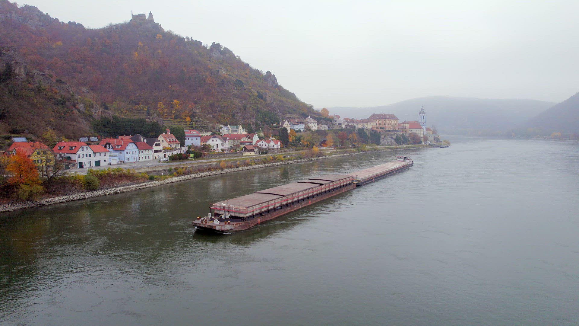 Cargo Pusher Boat on a River Transporting Cargo and Goods Past a Town