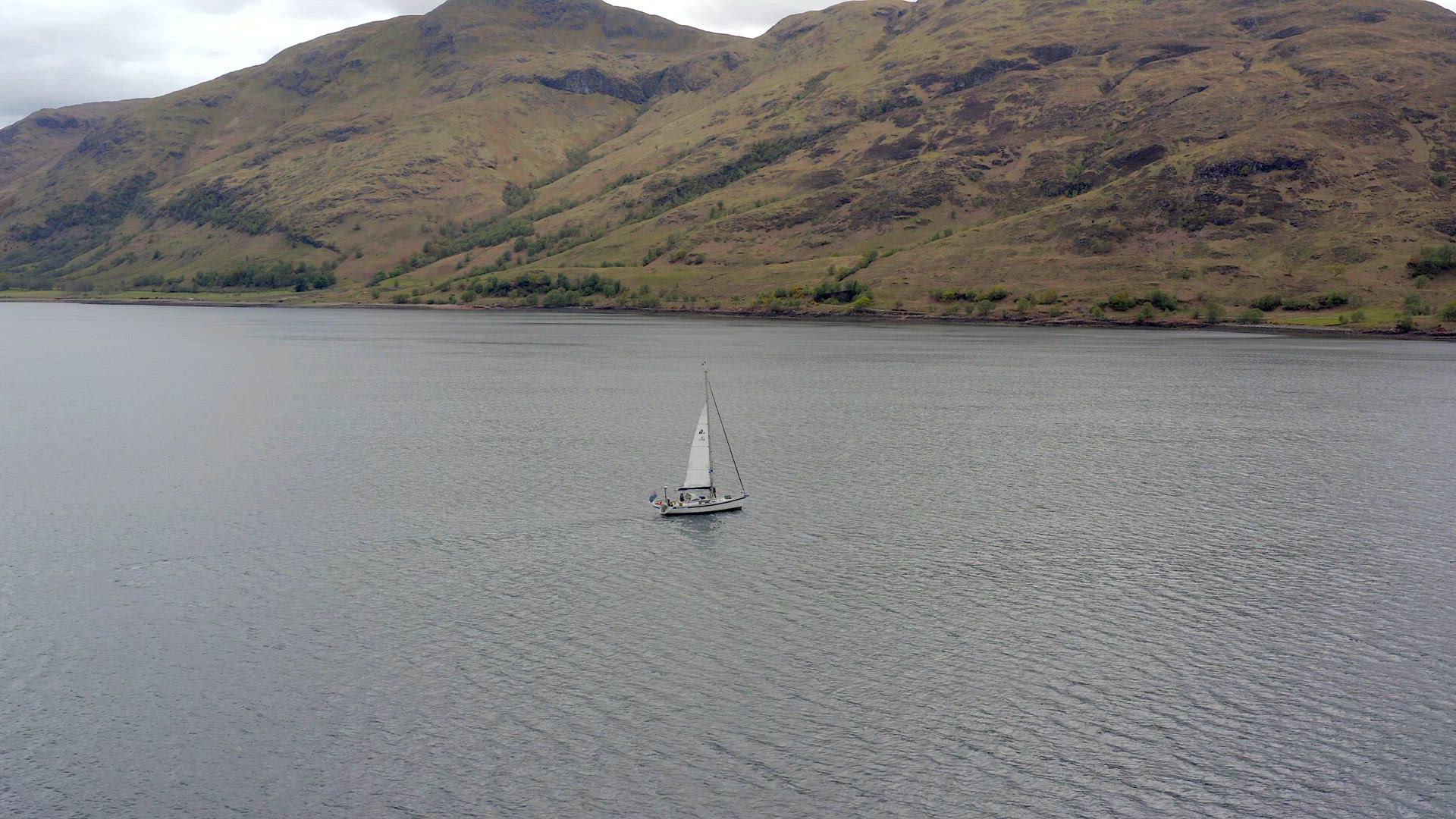 A Yacht Raising Sail Surrounded By Mountains and Forests in a Lake