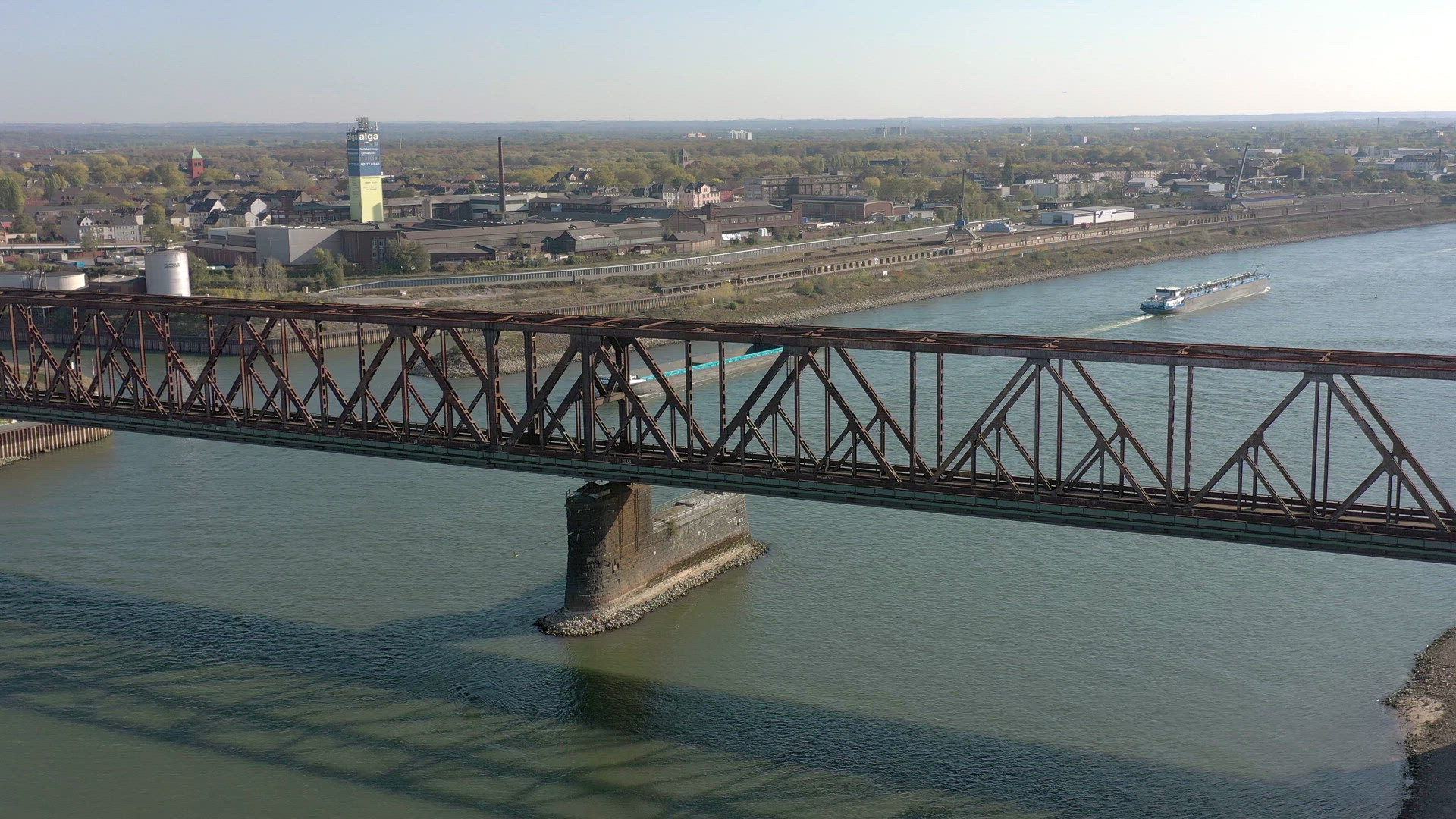 Train Passing Over a River Bridge with a Boat Moving Freight