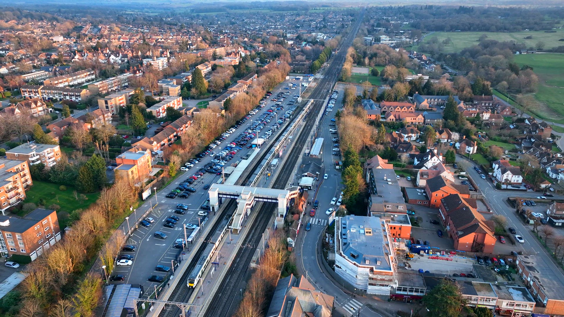 Commuter Train Approaching a Station in the UK Aerial View