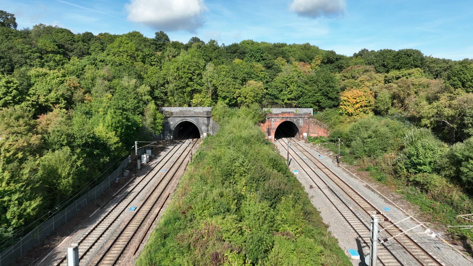 Commuter Train Speeding Under a Motorway in the UK Aerial View