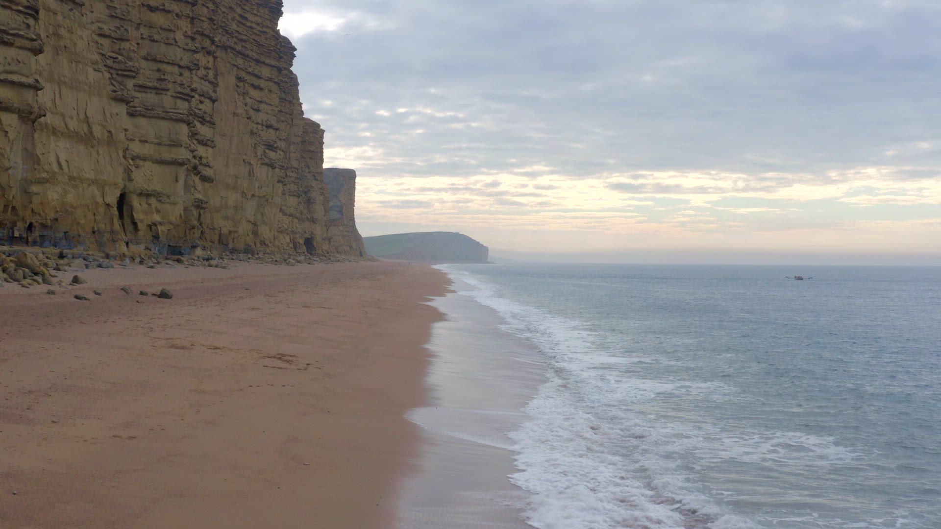 West Bay Beach With Tall Sandstone Cliffs Next the Sea in England