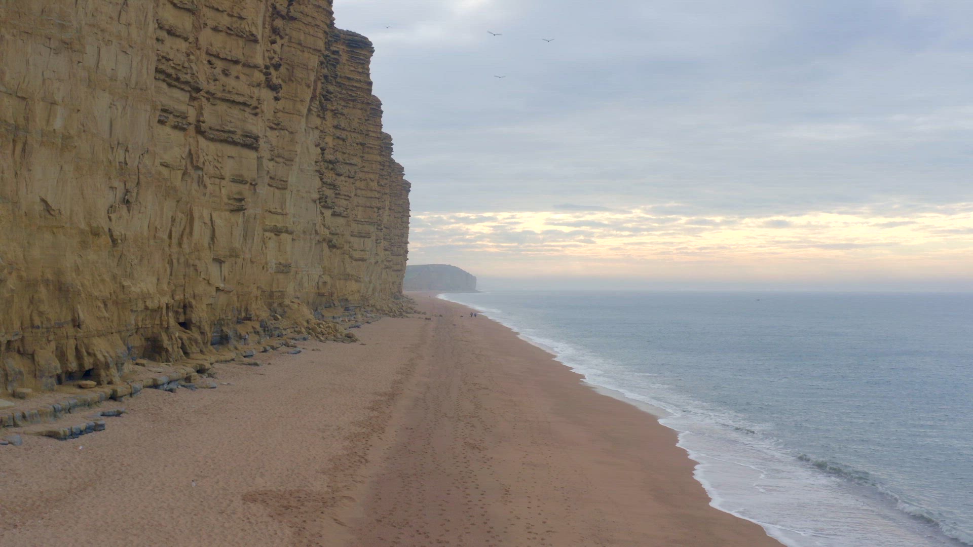 West Bay Beach With Tall Sandstone Cliffs Next the Sea in England