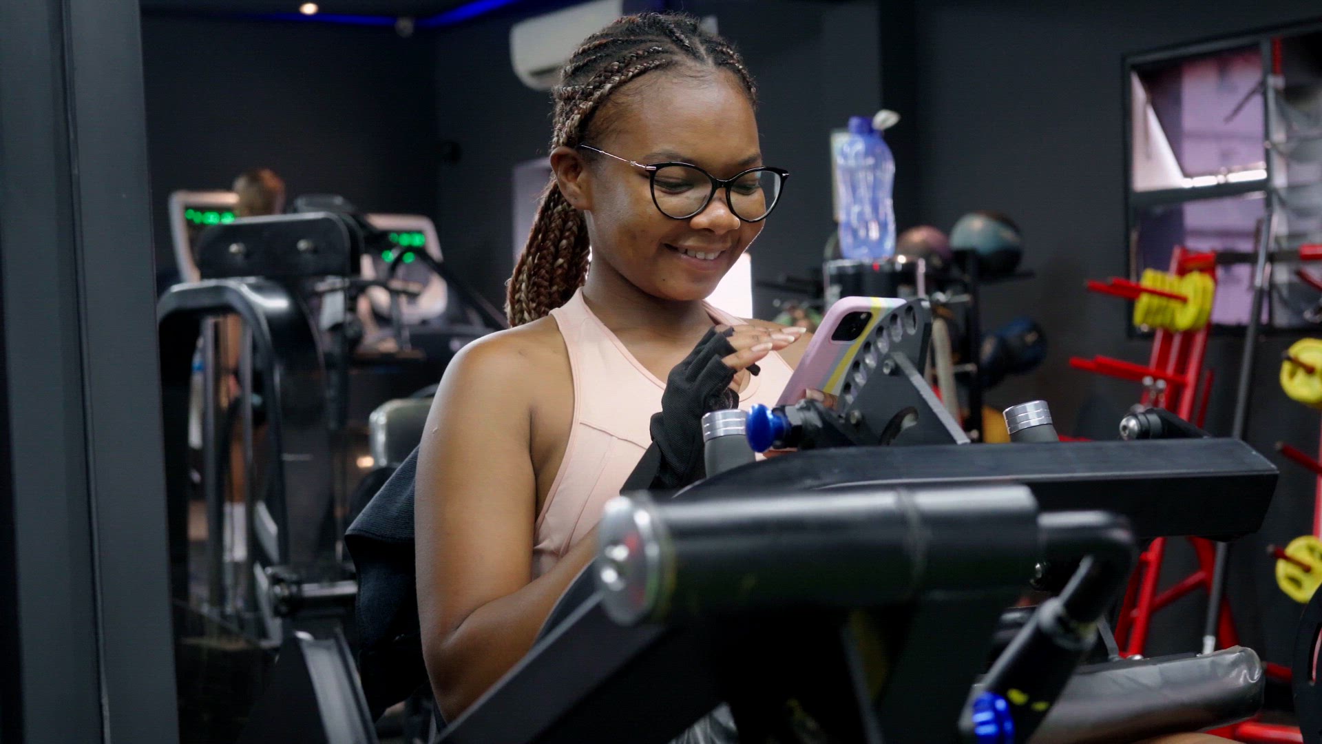 Woman sitting at the gym using a phone