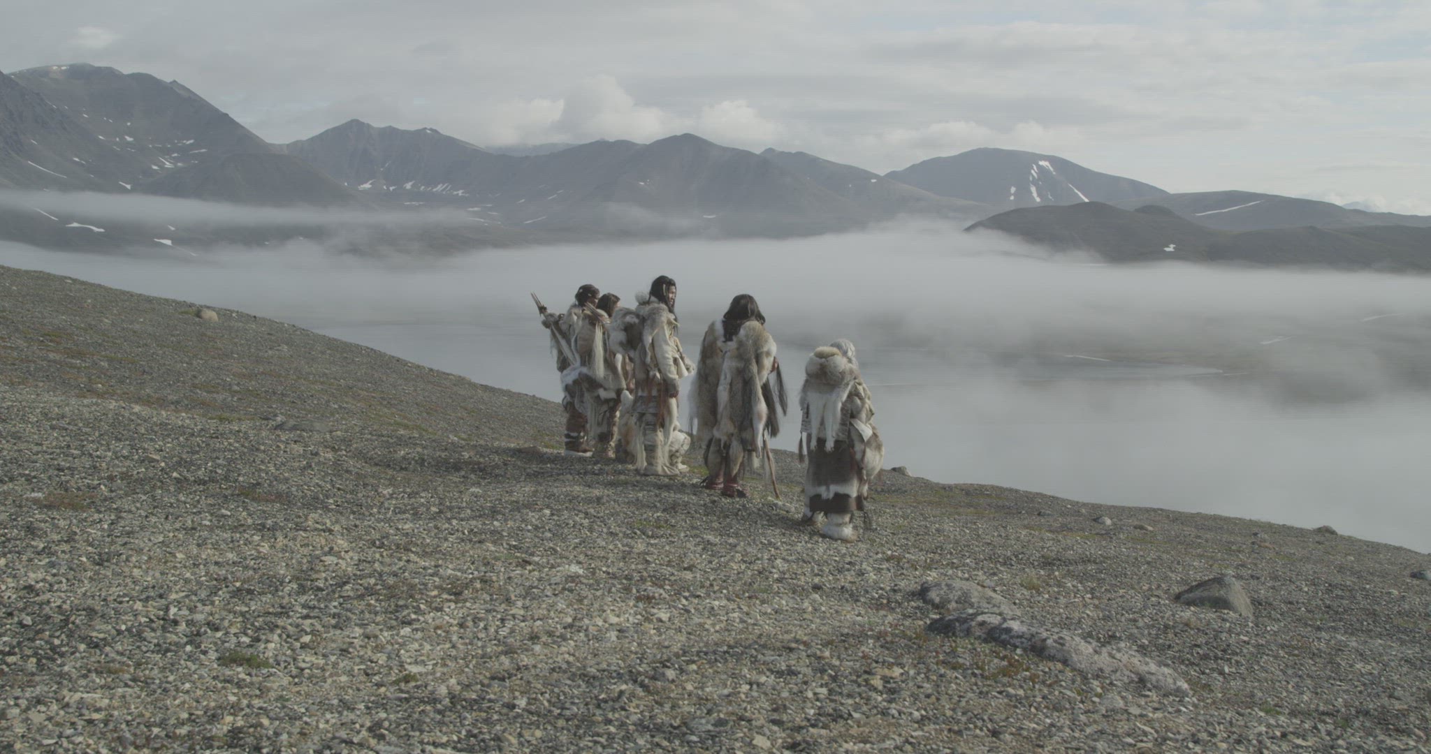 inuit hunters walking on mountain ridge