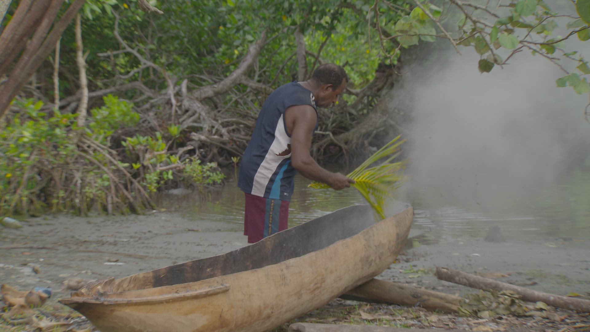 man burning inside of dug out canoe