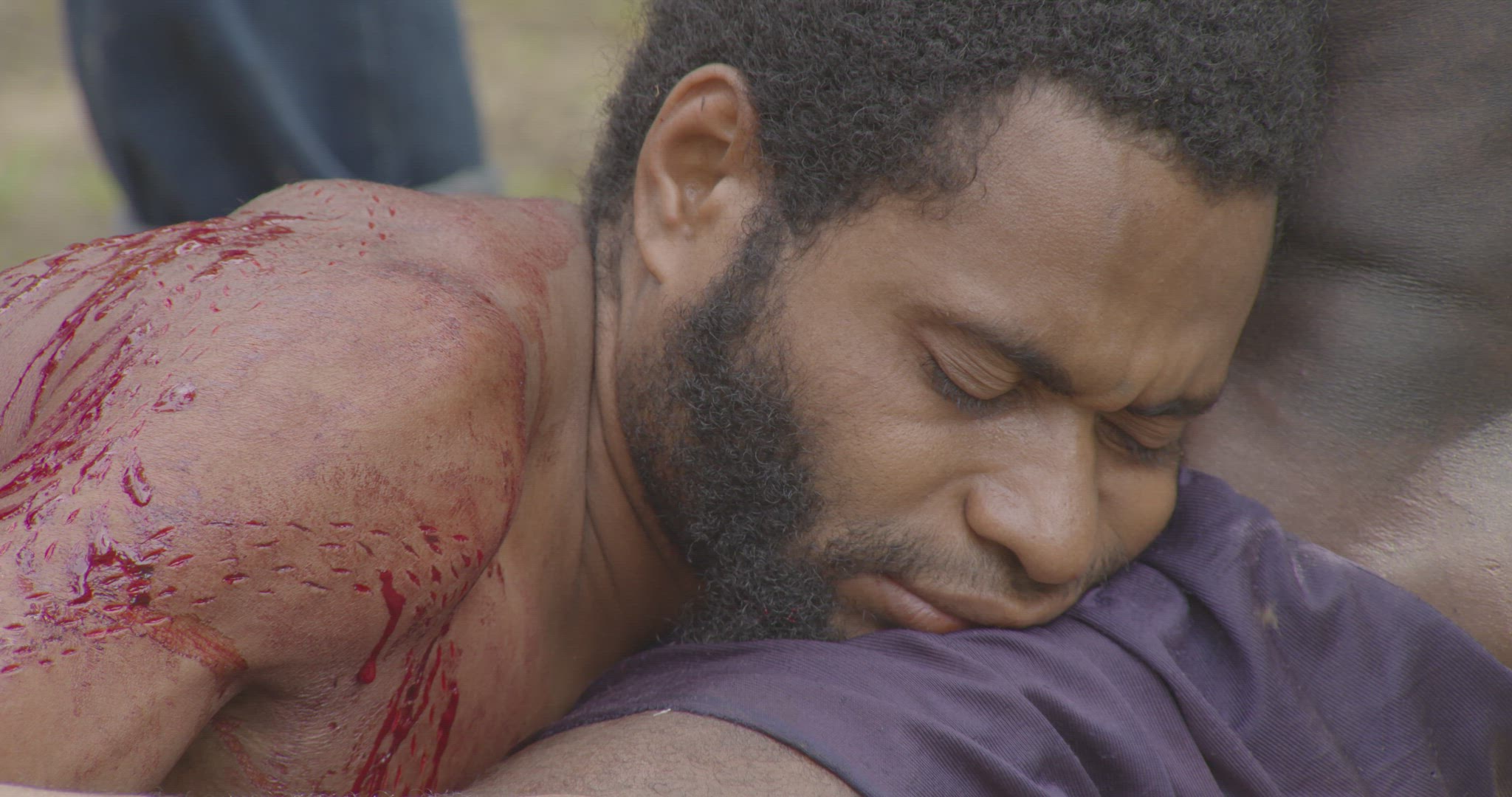 mans face as he is being cut during scarification ritual