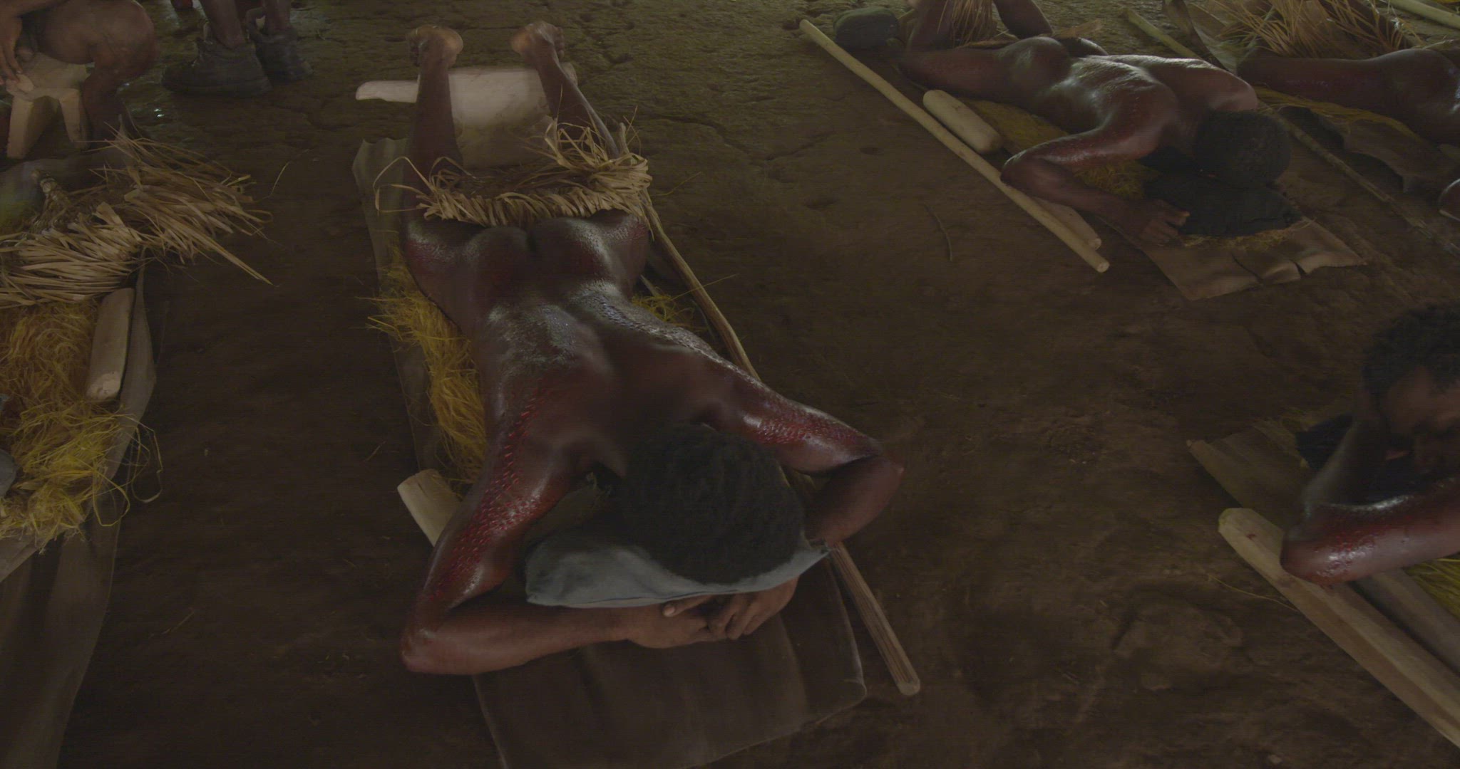 men laying on stomach after skin cutting ritual
