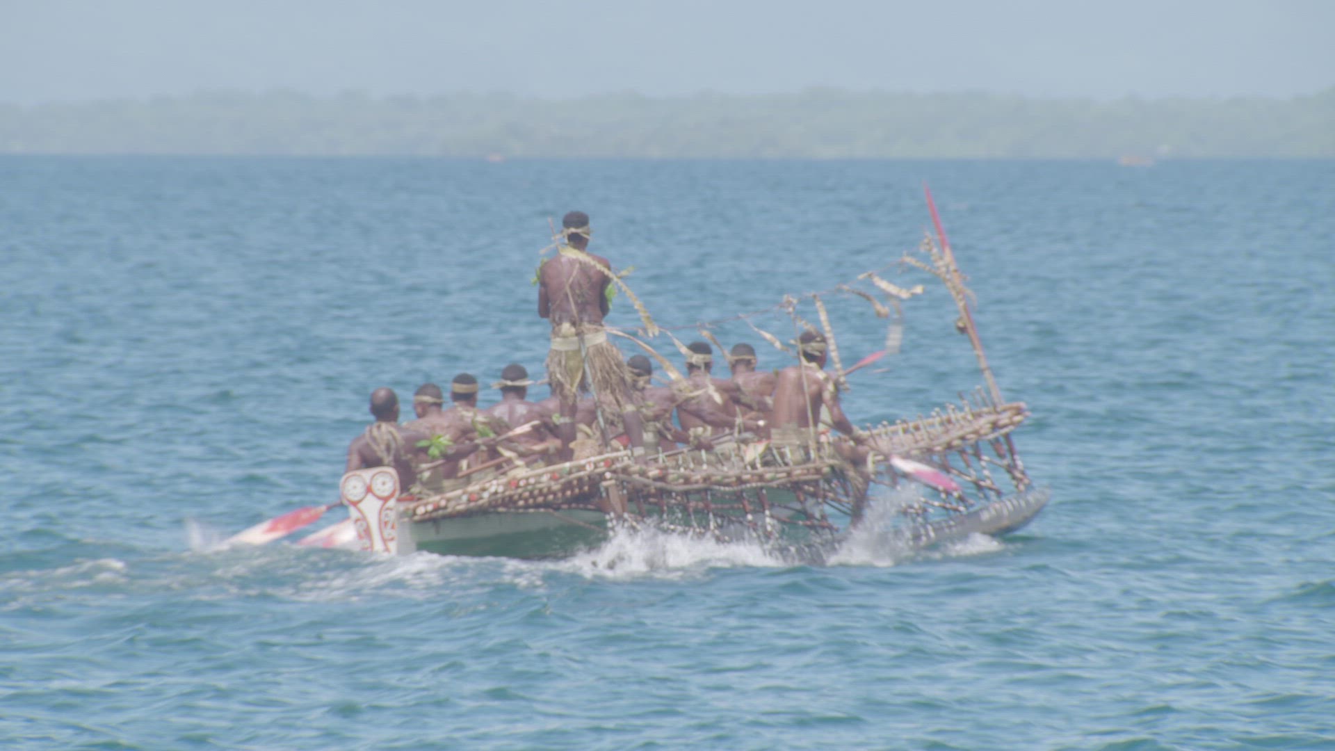 war canoe being paddled on water