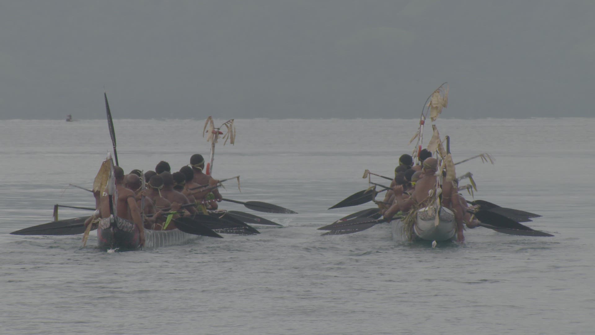 war canoe being paddled on water