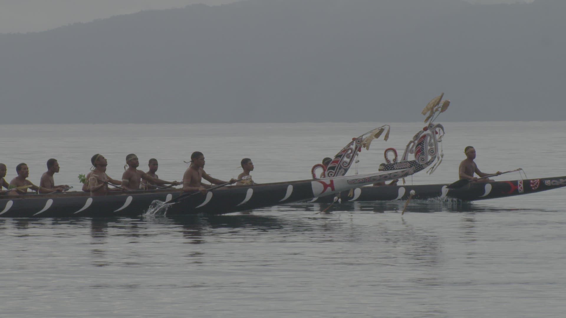 war canoe being paddled on water
